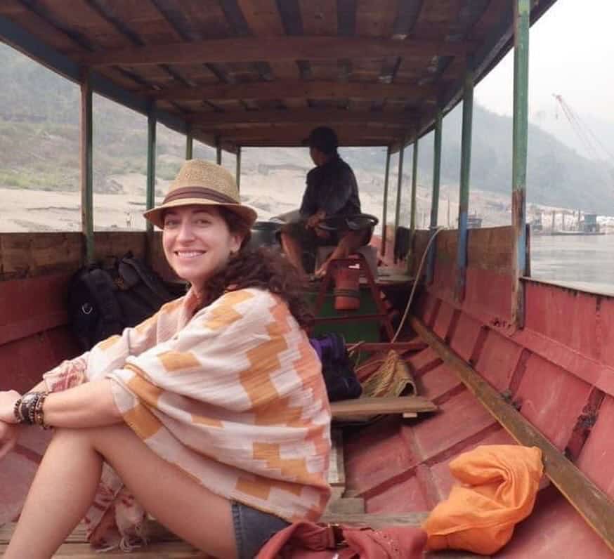 A woman rides a traditional long boat towards her luxury river cruise ship on the Mekong River.
