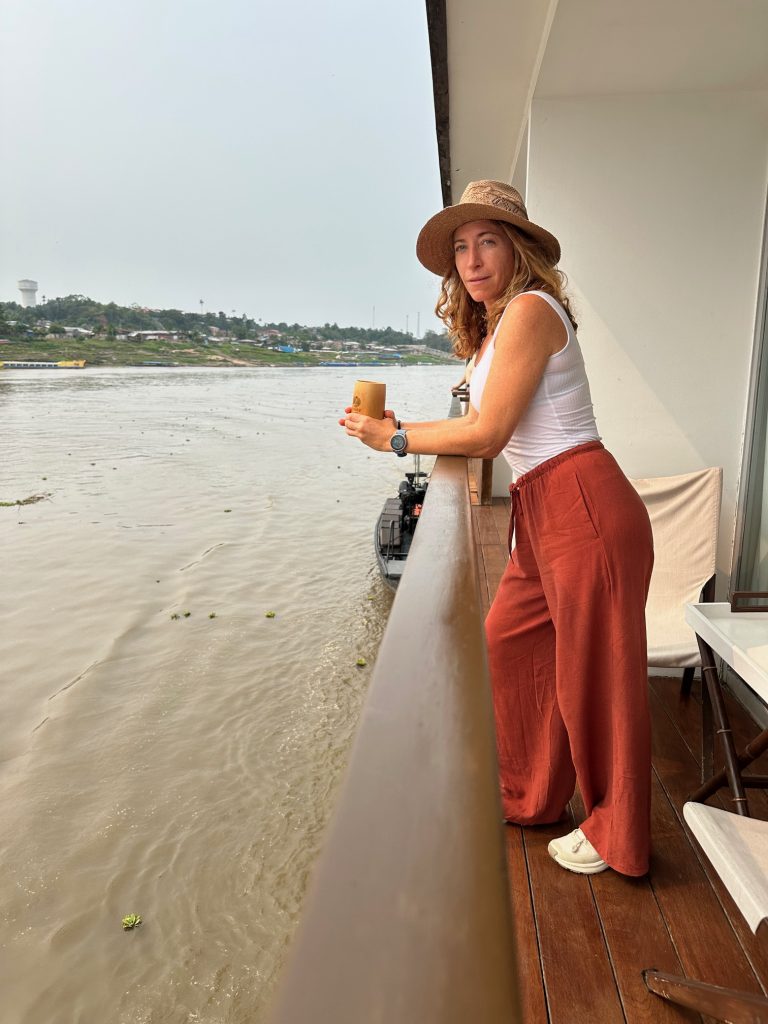 A woman stands on the balcony of her Amazon River cruise ship.
