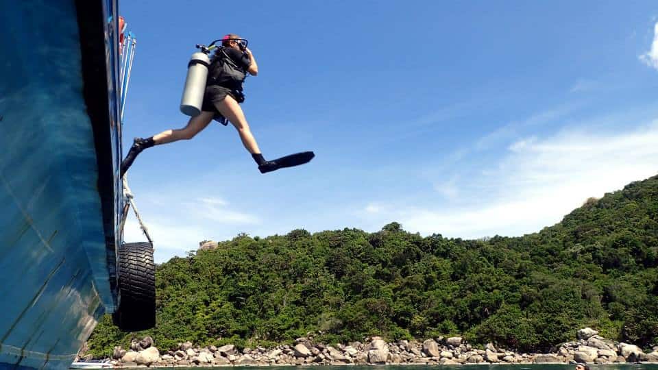 Dive professional does a giant stride into the water from a dive boat in Koh Tao, Thailand.