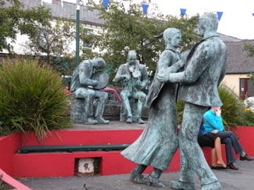 Weathered bronze statues of a band and a couple dancing stand in the square in Lisdoonvarna, Ireland.