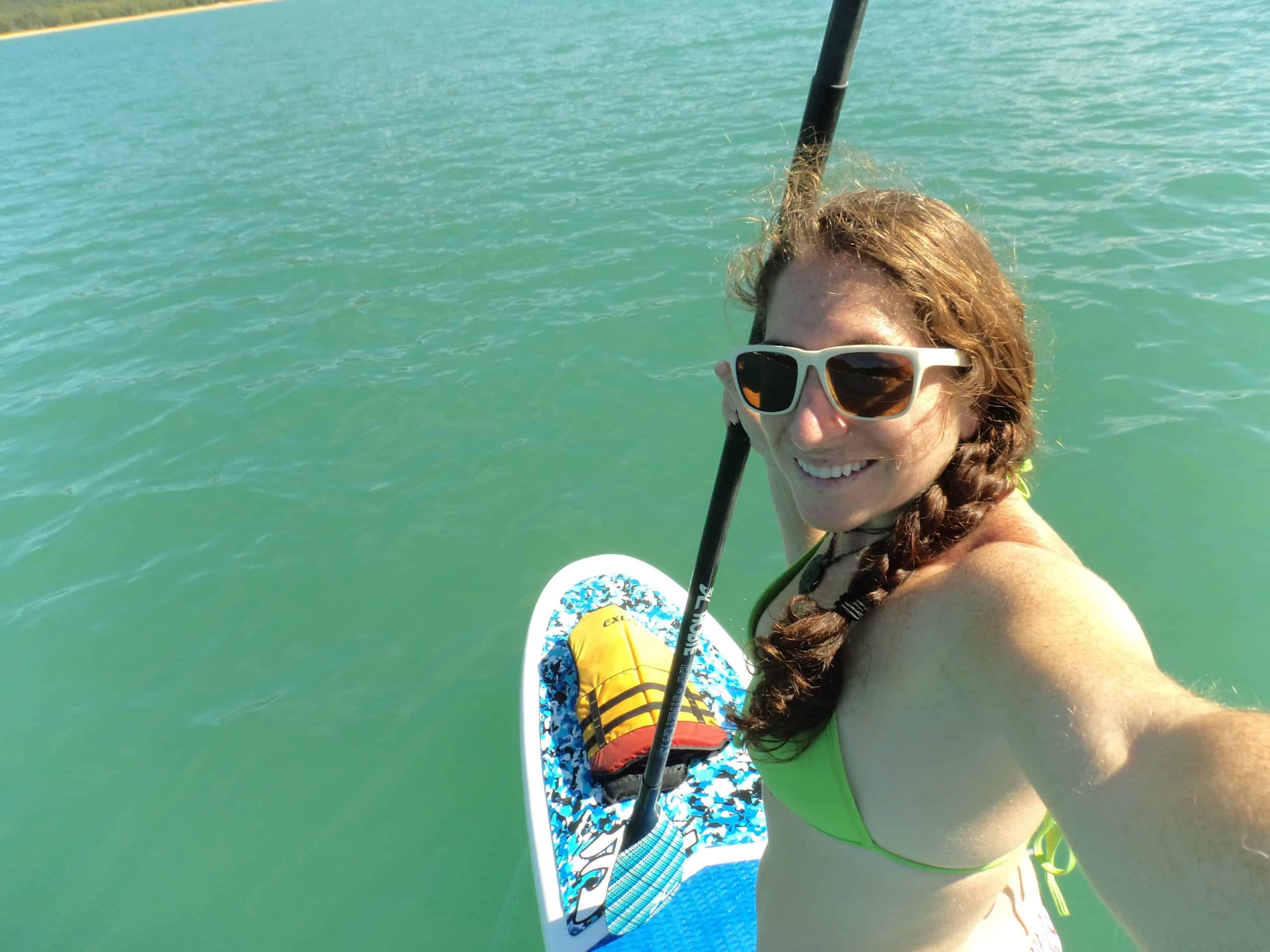 A woman paddleboards in a turquoise bay on Magnetic Island.