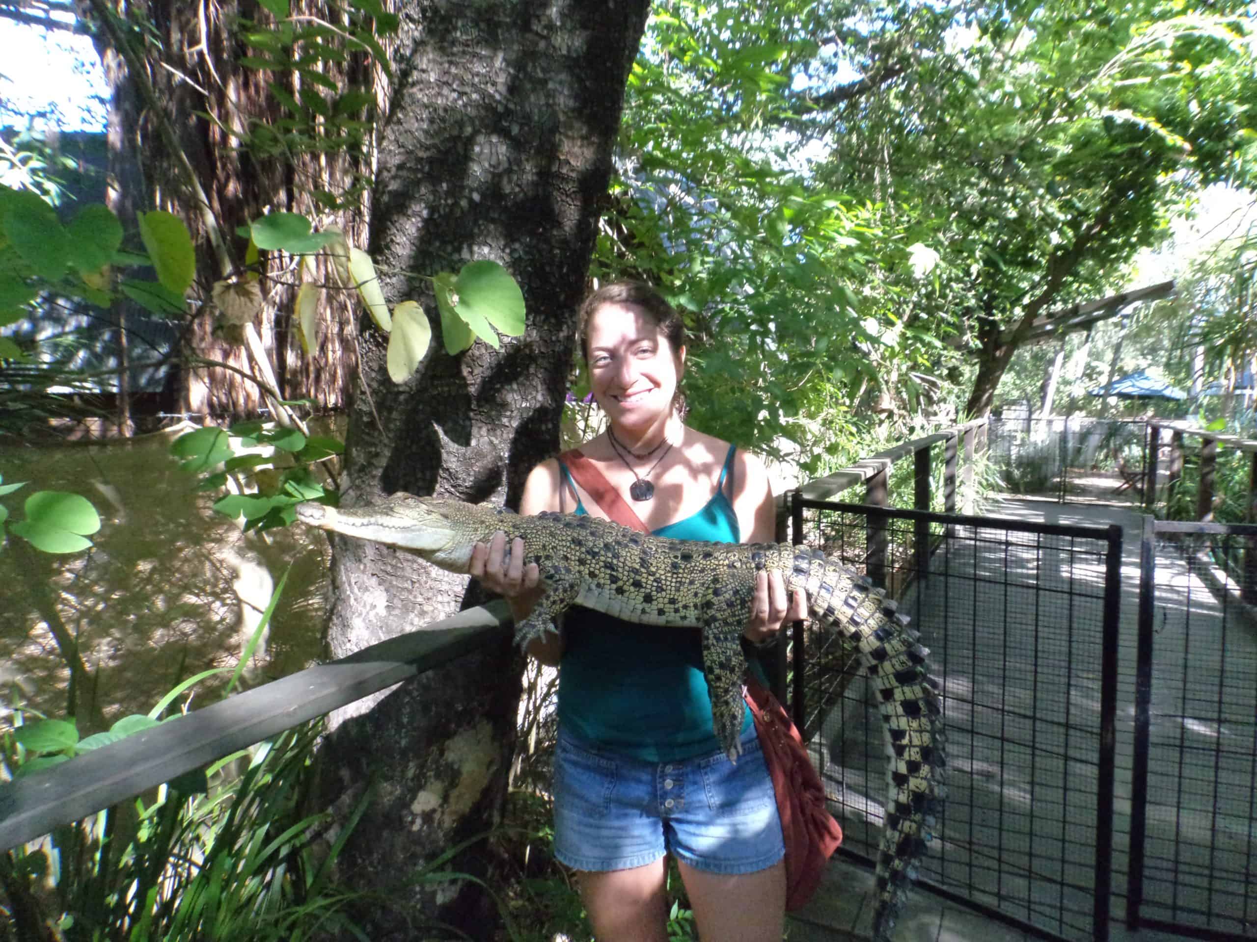 Woman holds a crocodile at a wildlife park on Magnetic Island in Australia.