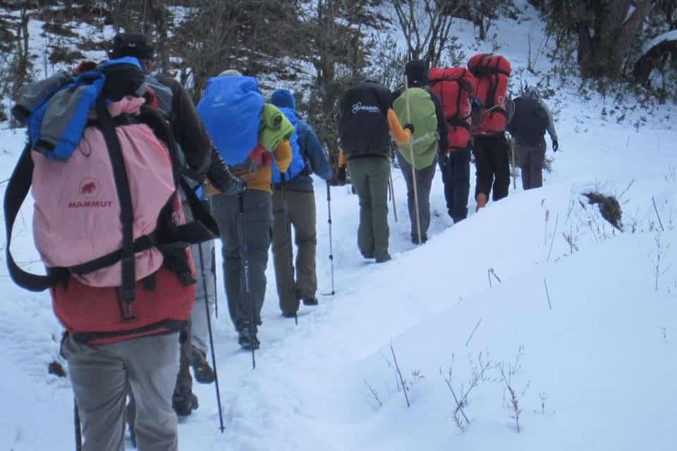 Trekkers hiking down a narrow snowy path on the Annapurna Circuit.