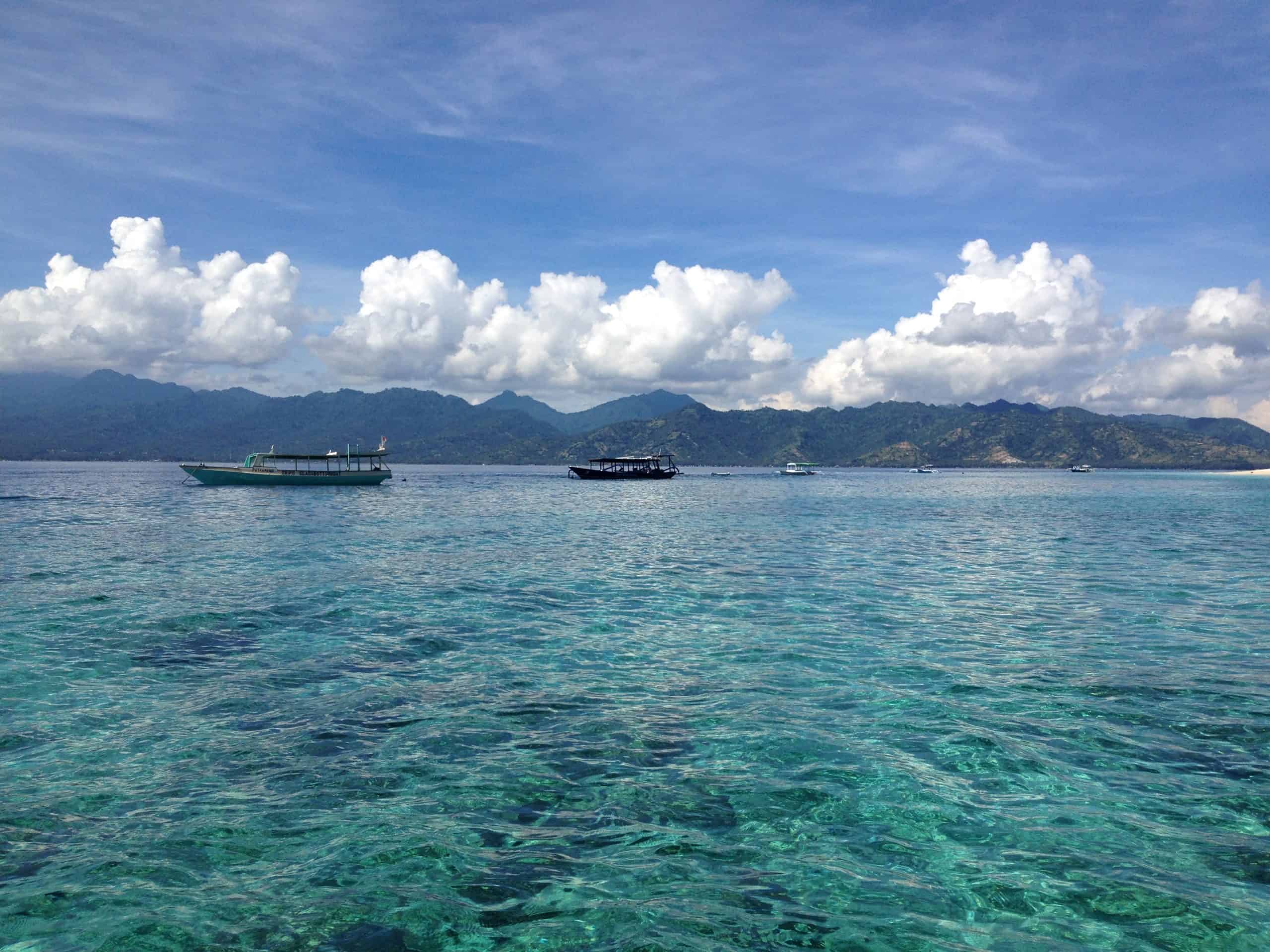 Boats floating in crystal clear waters off the coast of Bali.