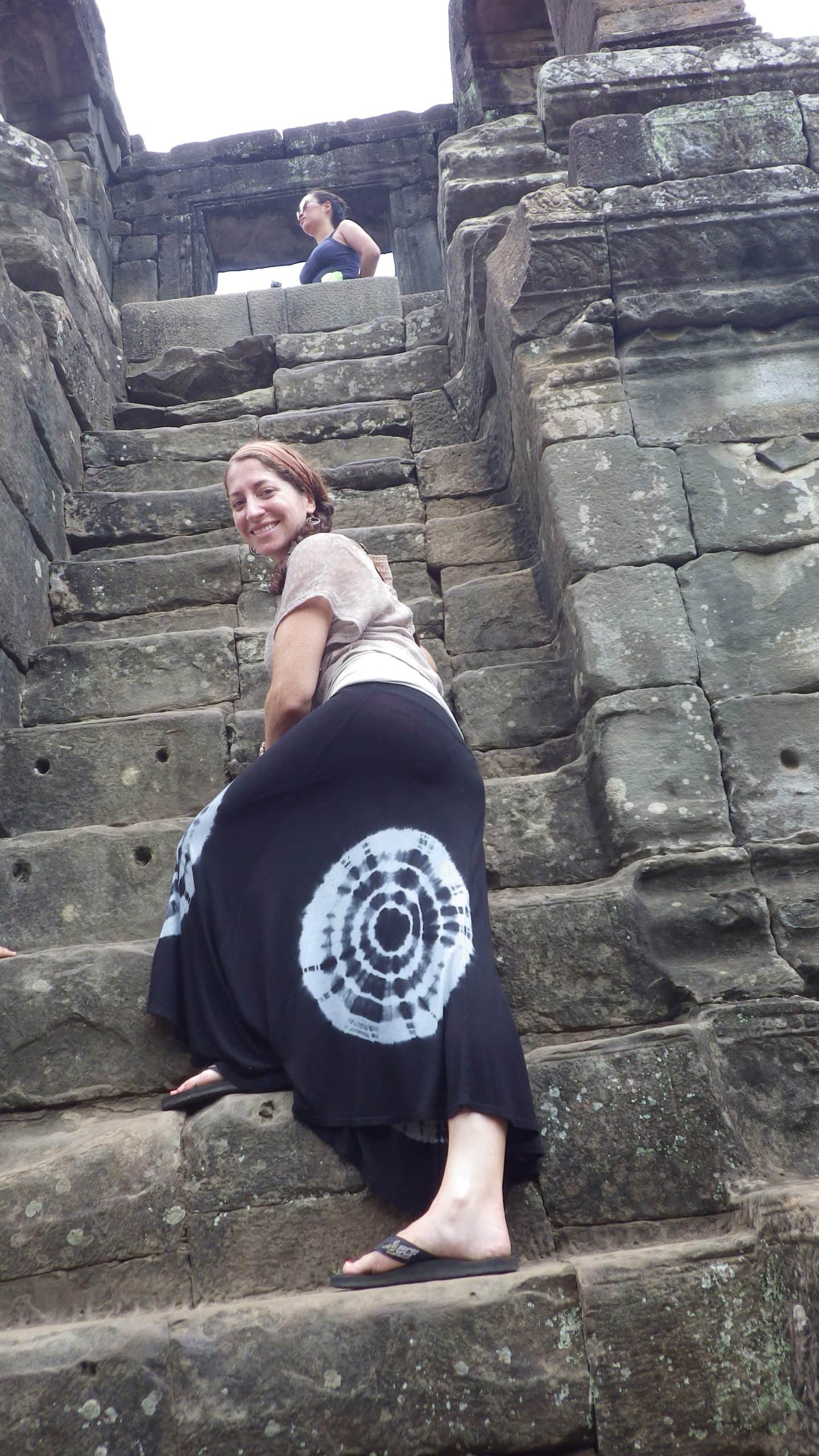 Woman climbs ruins in Cambodia.