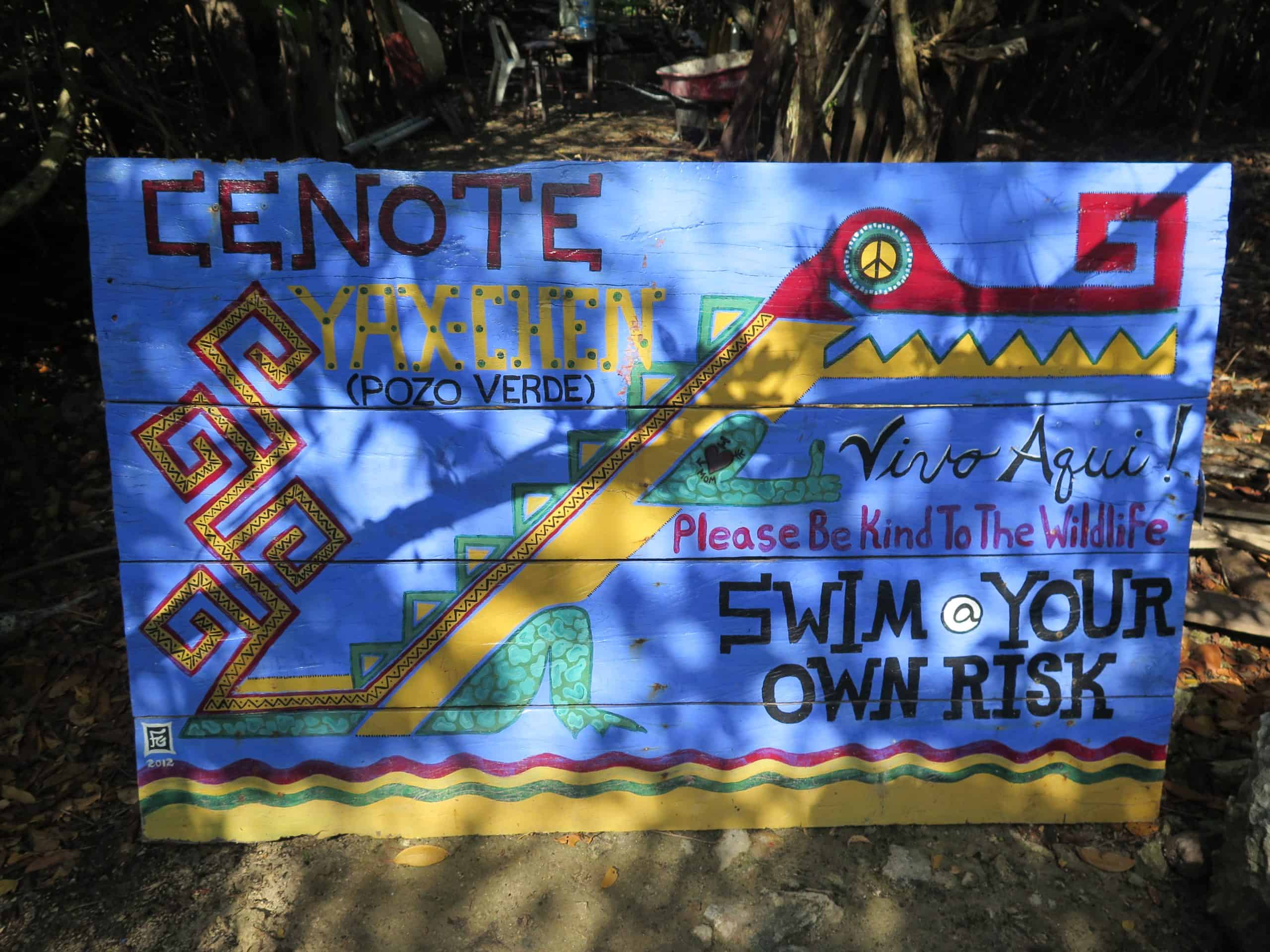 A sign for a cenote in Mexico read "dive at your own risk" and depicts a crocodile emblem.