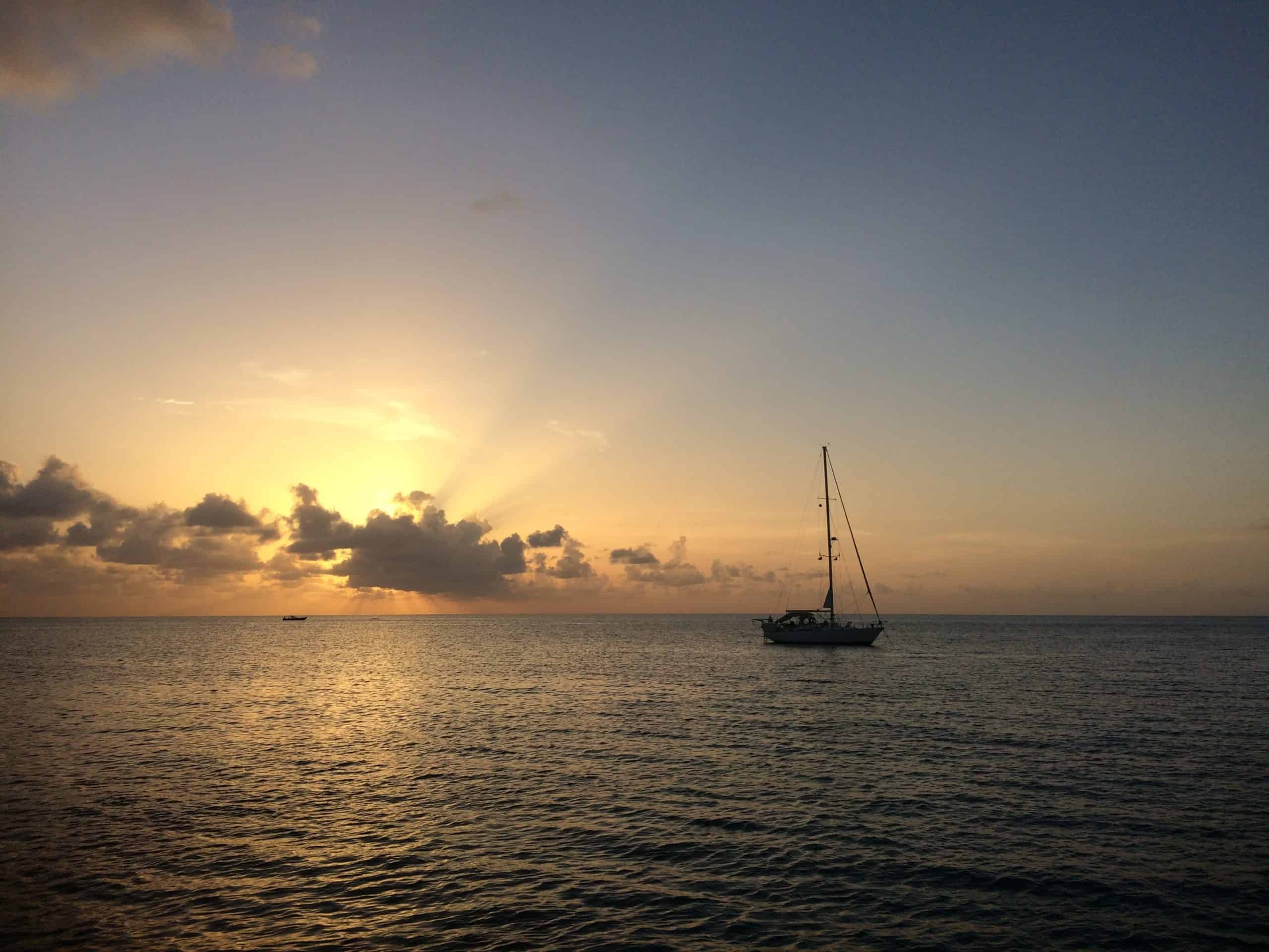 A liveaboard dive vessel floating in calm seas at sunset.
