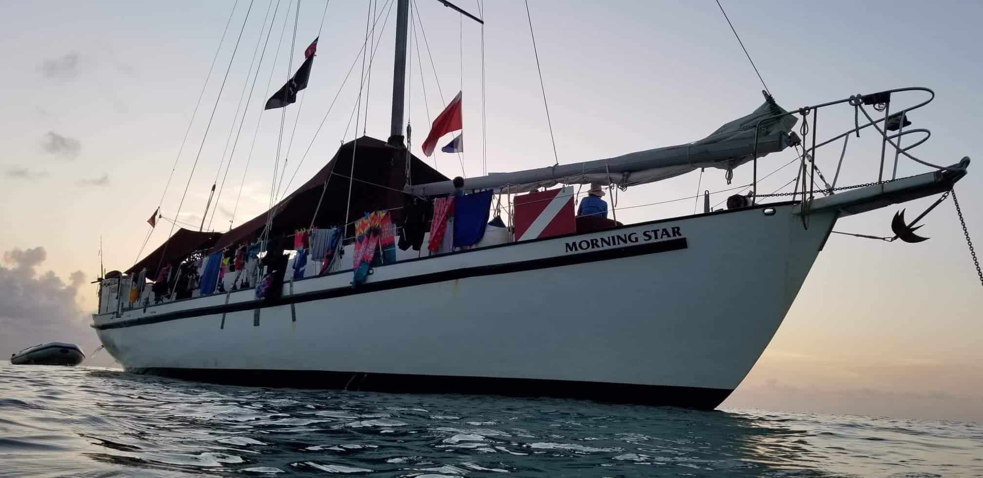 A liveaboard dive vessel floating in calm waters at dusk in the Bahamas
