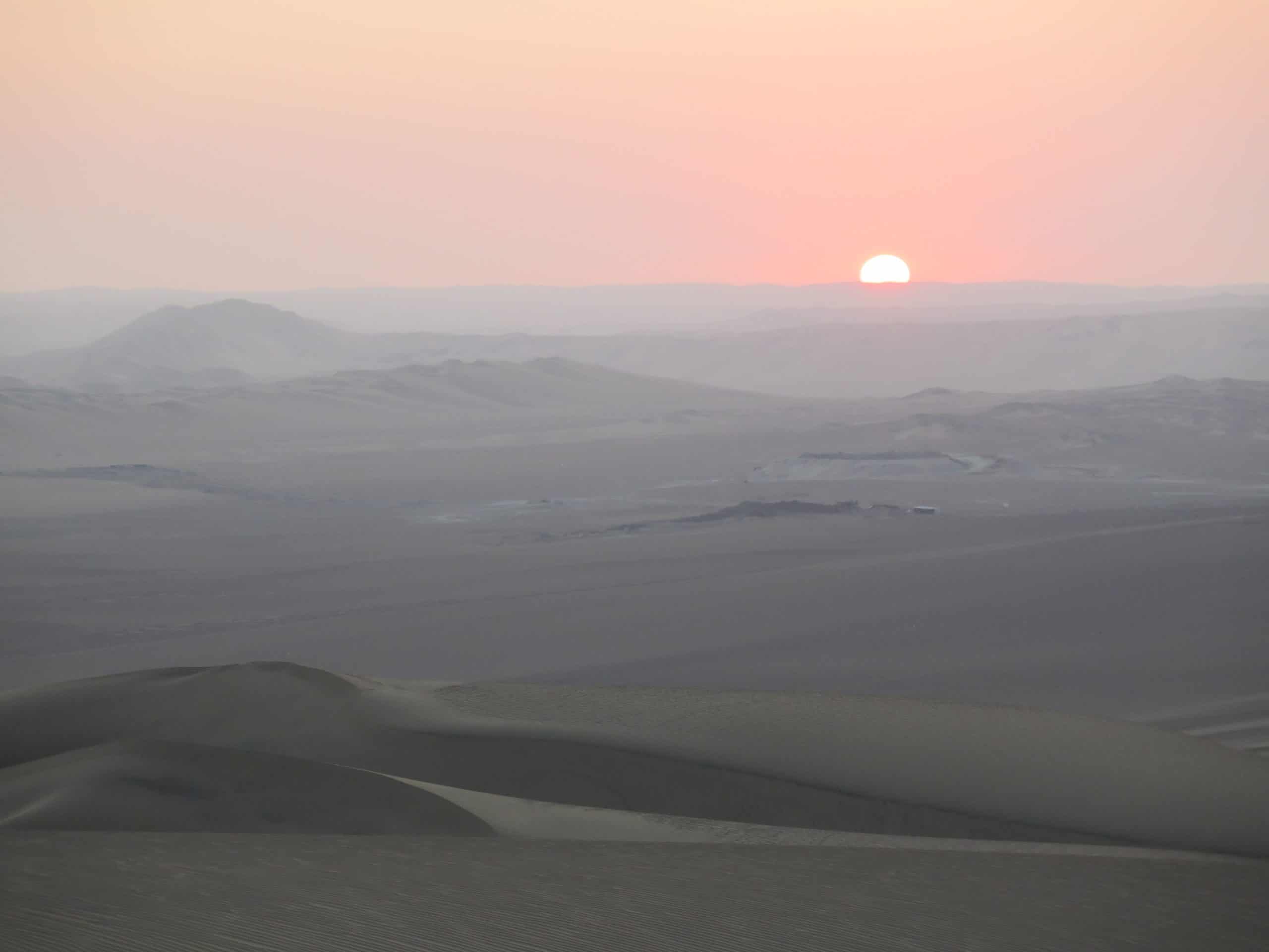 A hazy sunset in the desert at Huacachina Oasis in Peru.