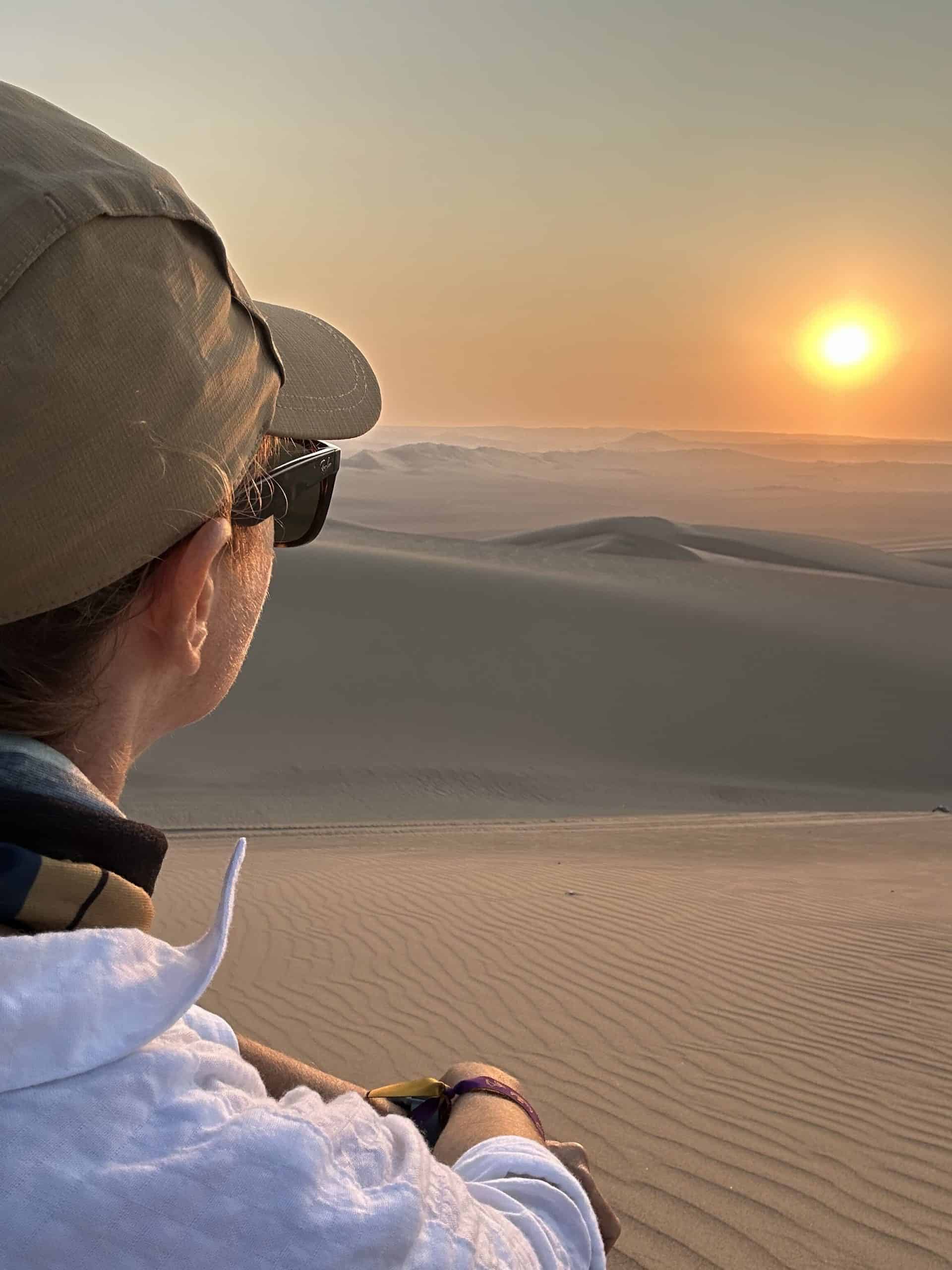 A woman appreciates the gorgeous sunset over the dunes of the Ica desert on her Huacachina Oasis tour from Lima.