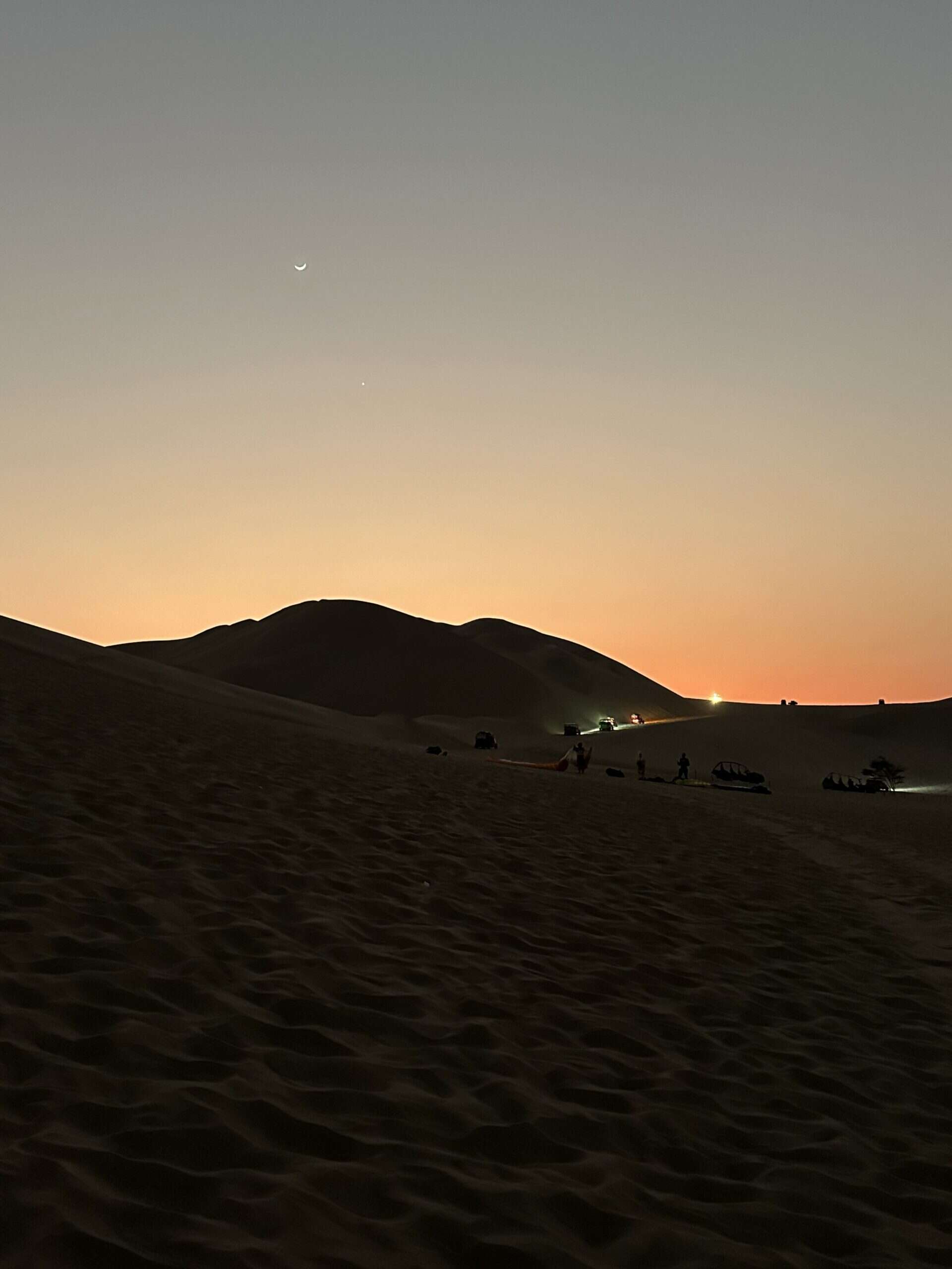 On the Huacachina Oasis tour from Lima, dune buggies surf the dunes as night falls over the desert.