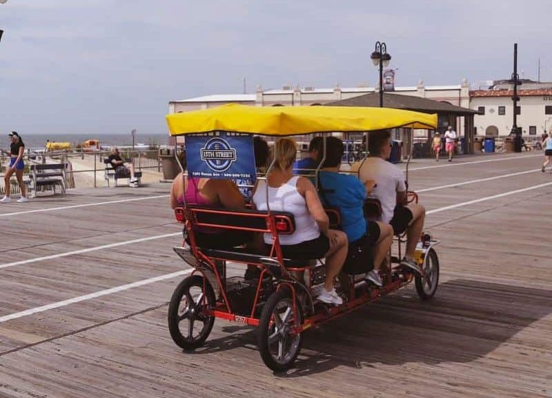 Visitors to Ocean City, NJ ride a surrey on the boardwalk.