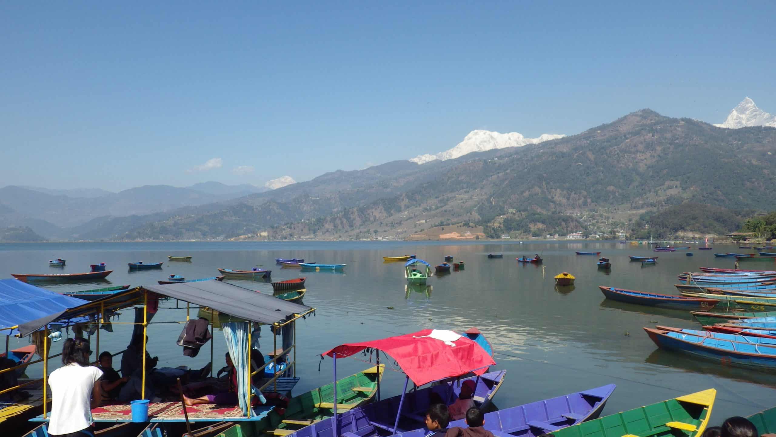 A calm lake filled with colorful boats in Pokhara, Nepal.