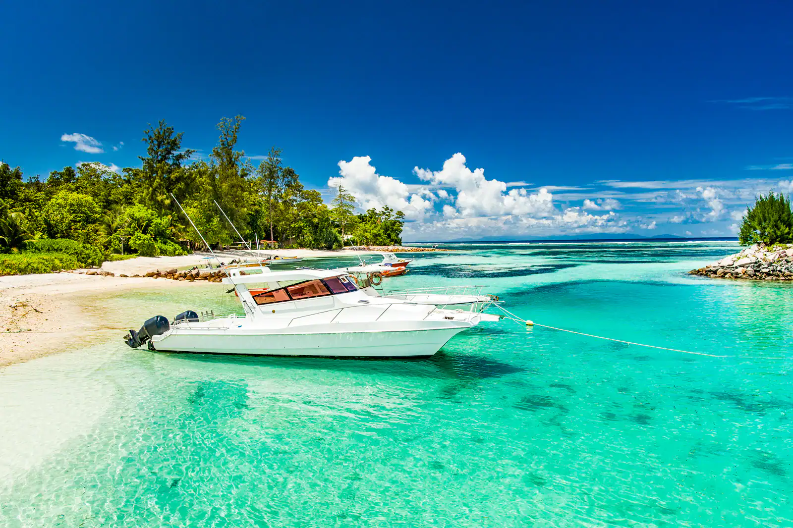 A luxury chartered boat anchored in turquoise waters on a beach in the Seychelles. 