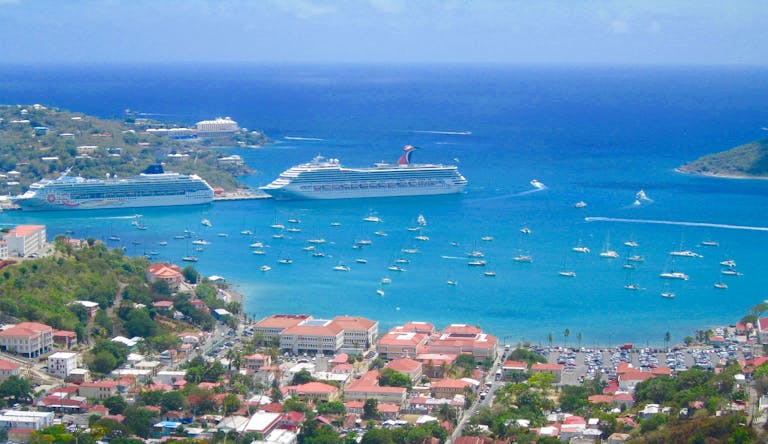 Scenic aerial view of a tropical harbor in the Eastern Caribbean with cruise ships and sailboats in clear blue waters.