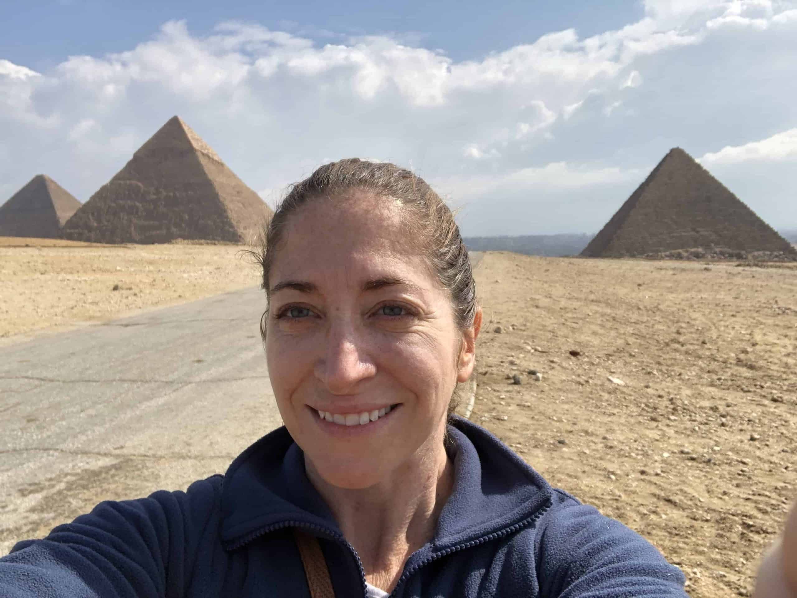 Woman takes a selfie in front of the Great Pyramids of Giza in Cairo, Egypt.