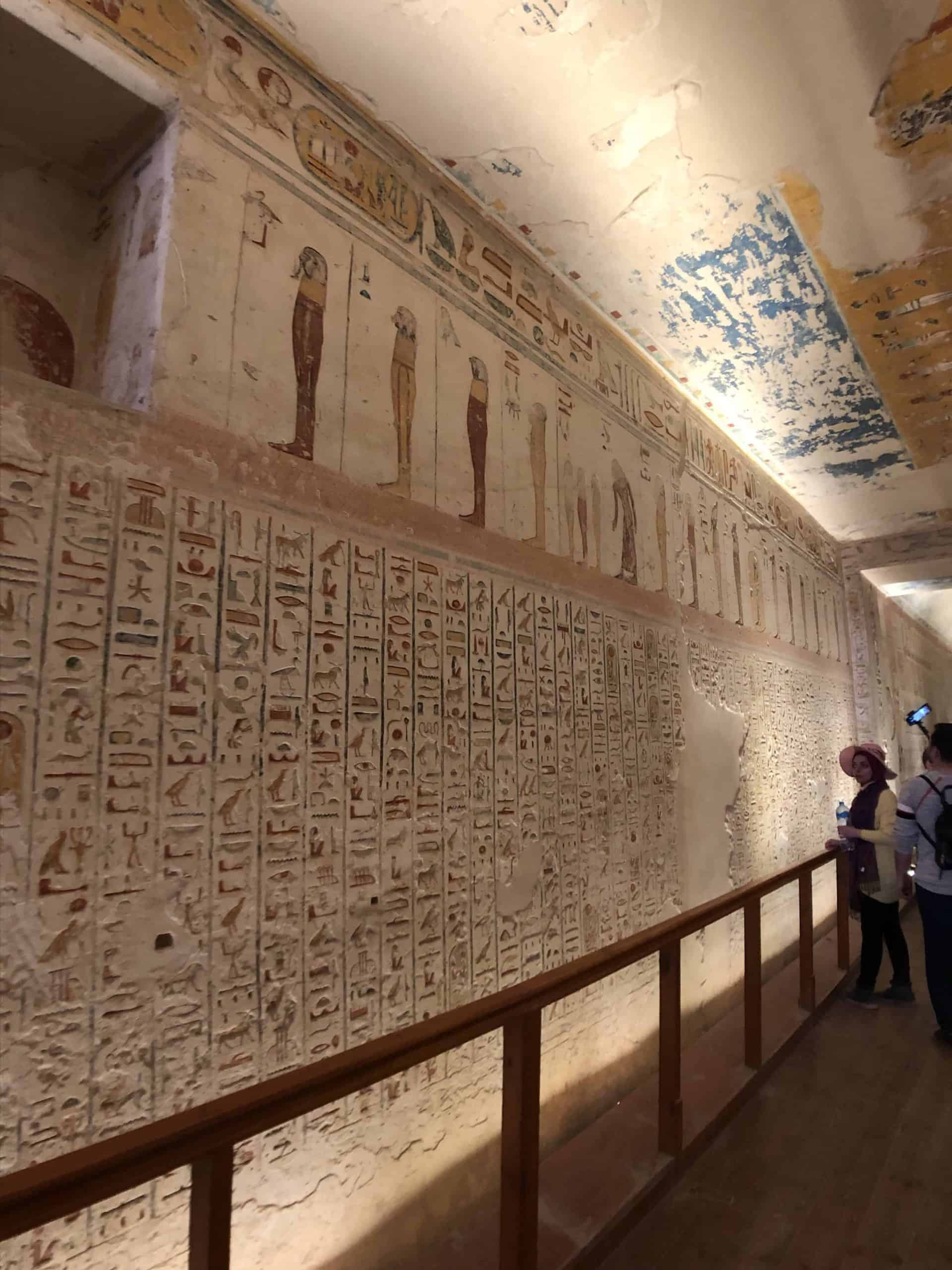 White tunnel walls covered in colorful hieroglyphs leading into a pharaohs tomb at the Valley of the Kings in Egypt.