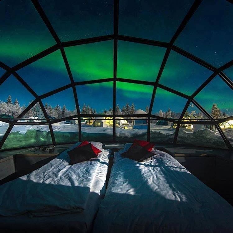 The Northern Lights shine in shades of green viewed from inside an igloo hotel in the arctic.