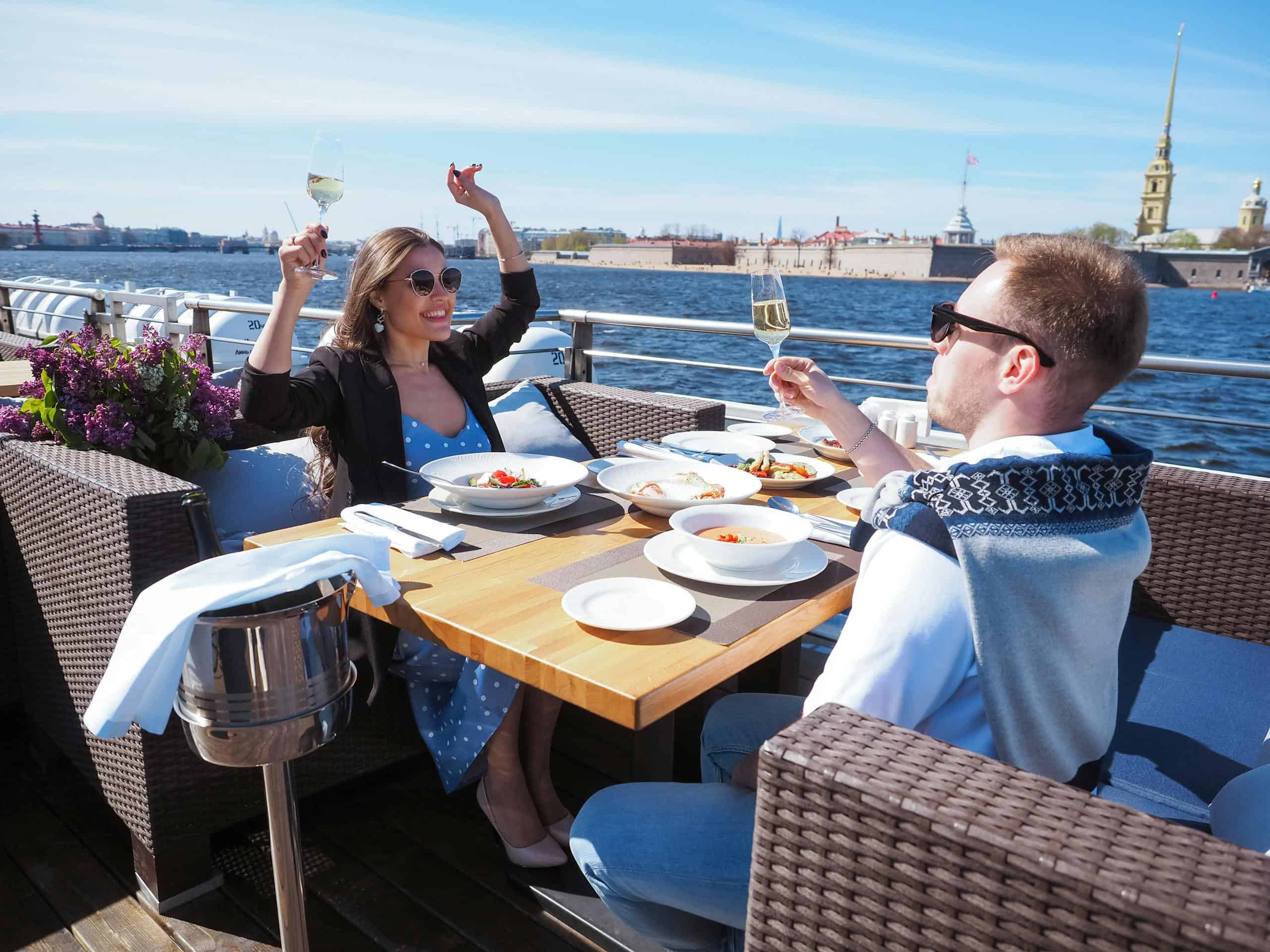 Couple enjoying a romantic meal on a river cruise with a scenic view.