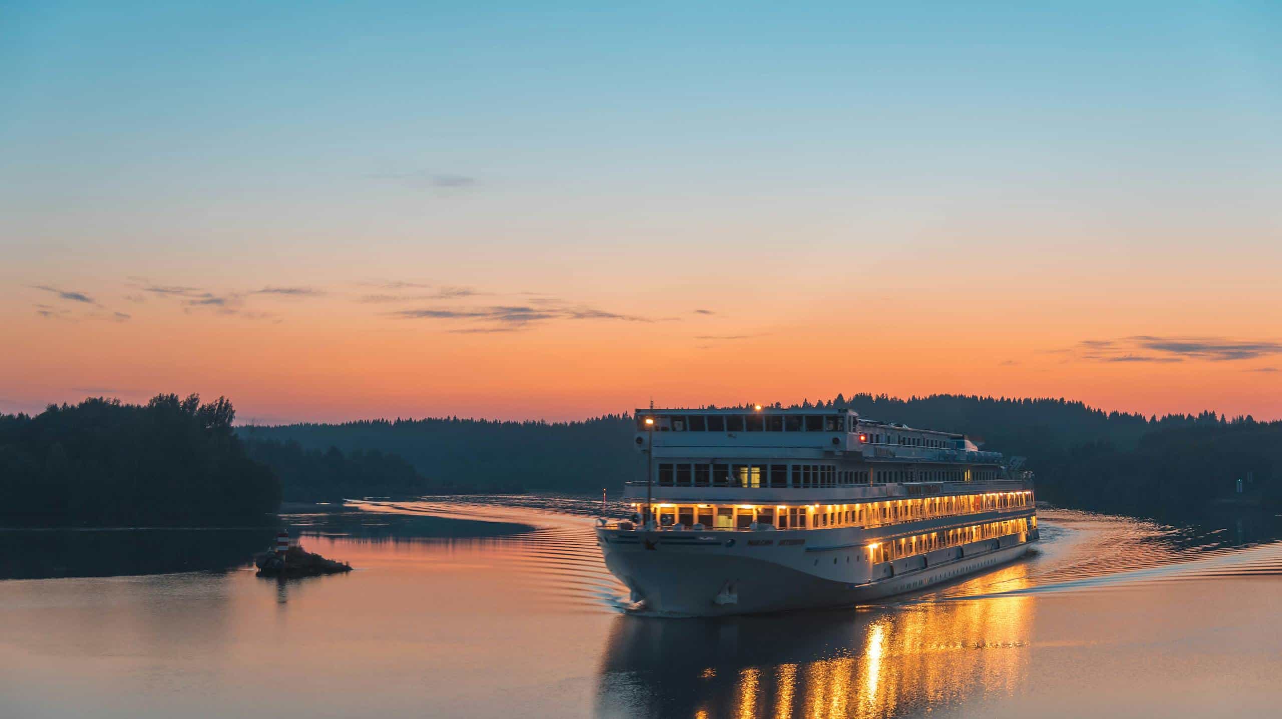 Elegant river cruise ship gliding along at sunset, reflecting the serene beauty of the surrounding landscape.