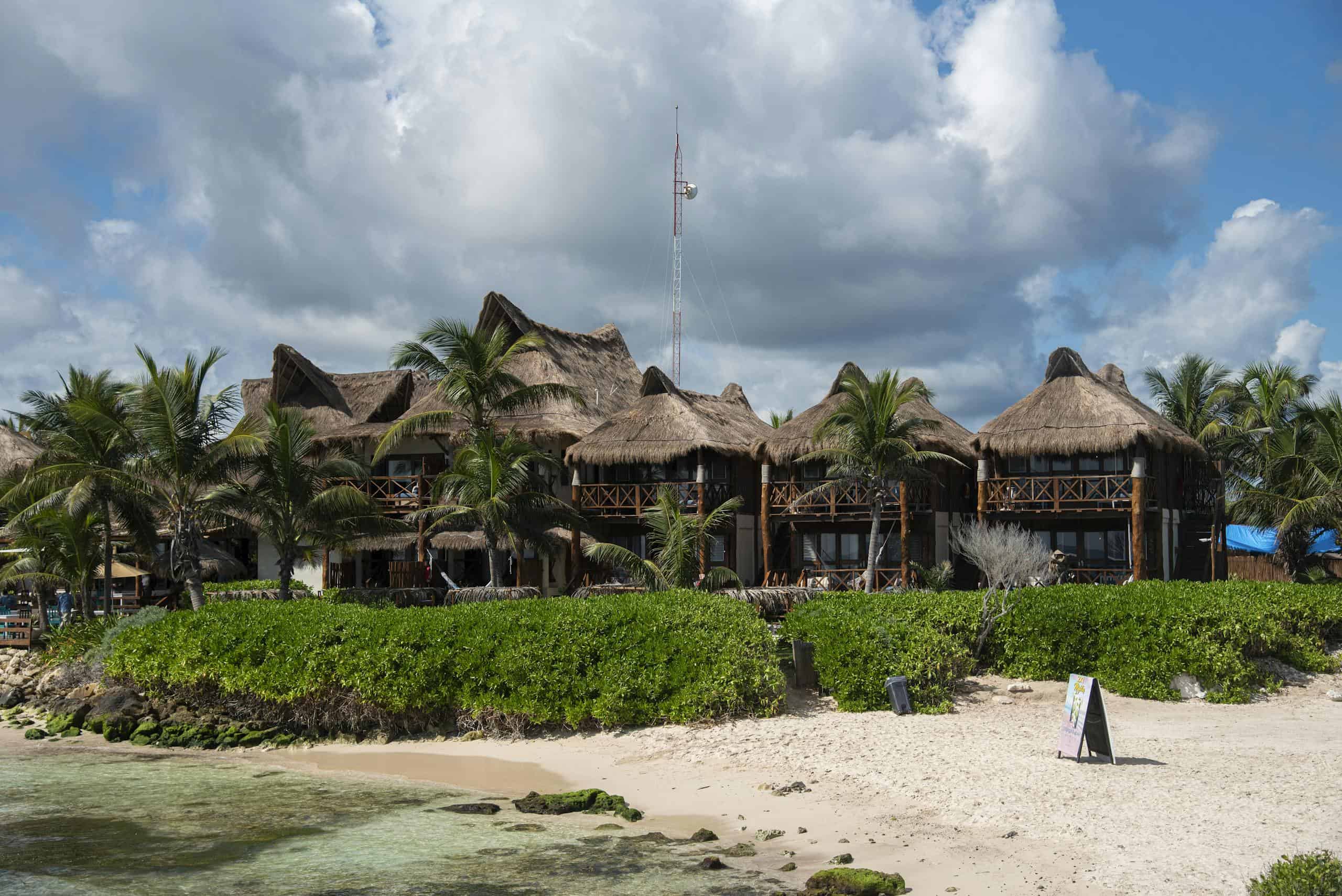 Tropical beach resort with palapa roofs and palm trees in Tulum, Mexico.