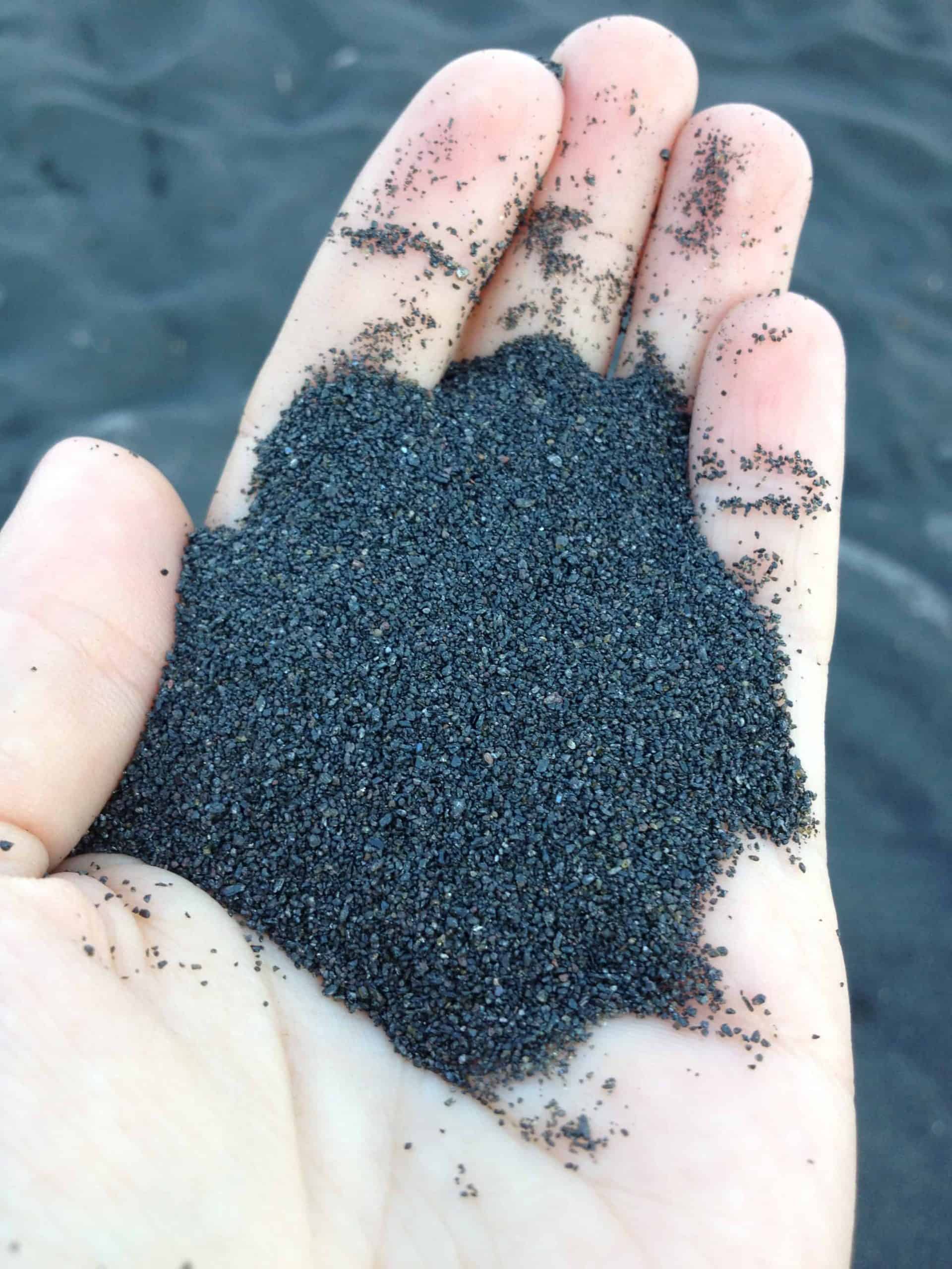 A hand holding black sand from a beach on Stromboli island.