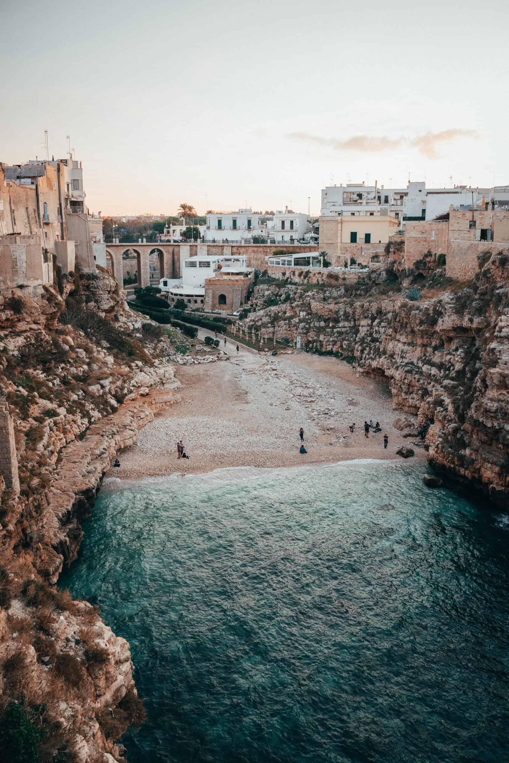 Breathtaking view of Polignano a Mare's rocky cliffs and serene beach, perfect for summer vacations.
