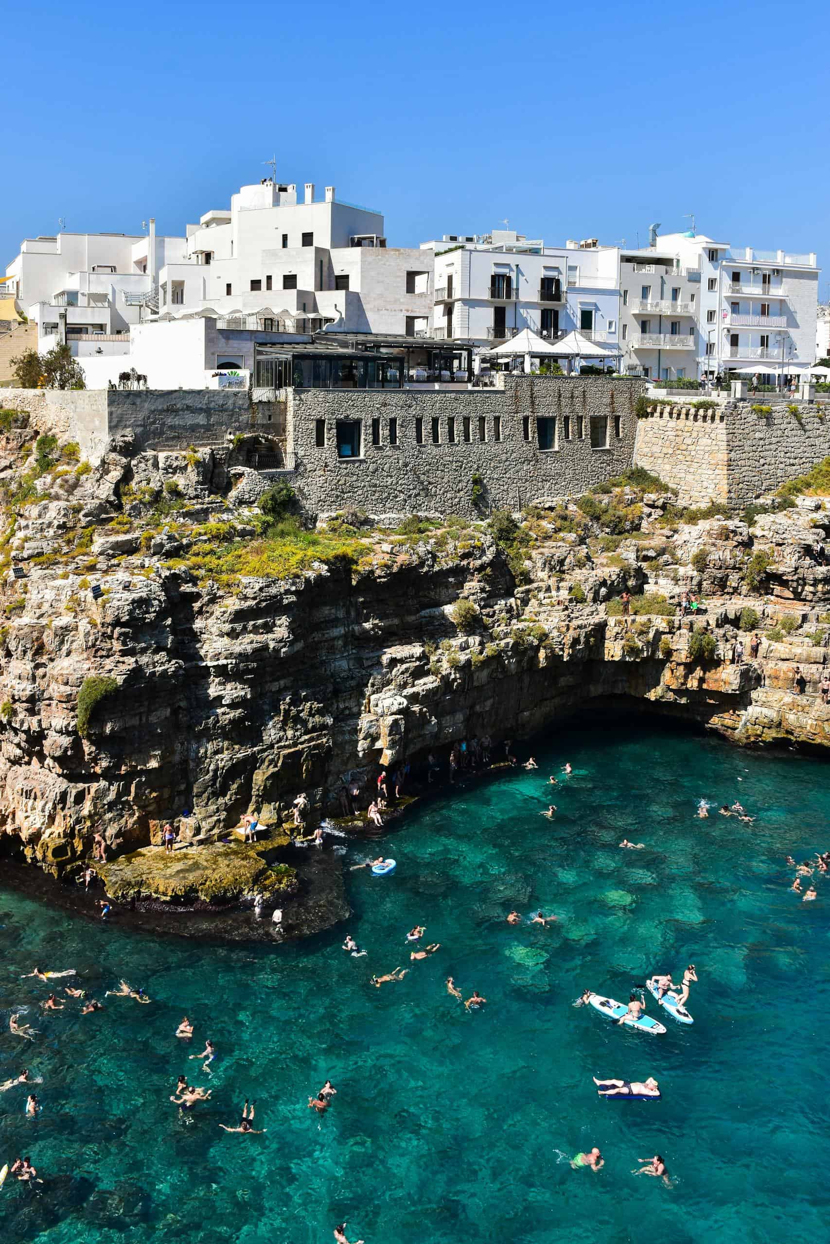 Swimmers enjoy the turquoise waters below the cliffs of Polignano a Mare in Italy.