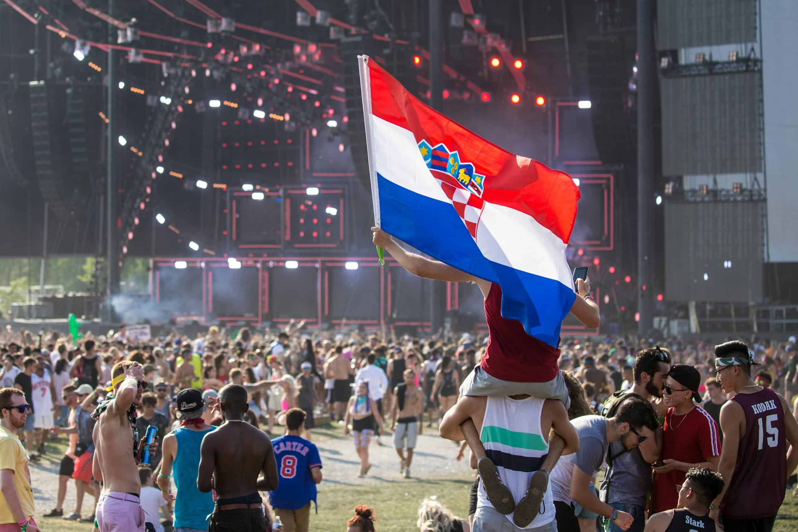 Vibrant festival crowd enjoying a lively outdoor event with a Croatian flag displayed prominently.