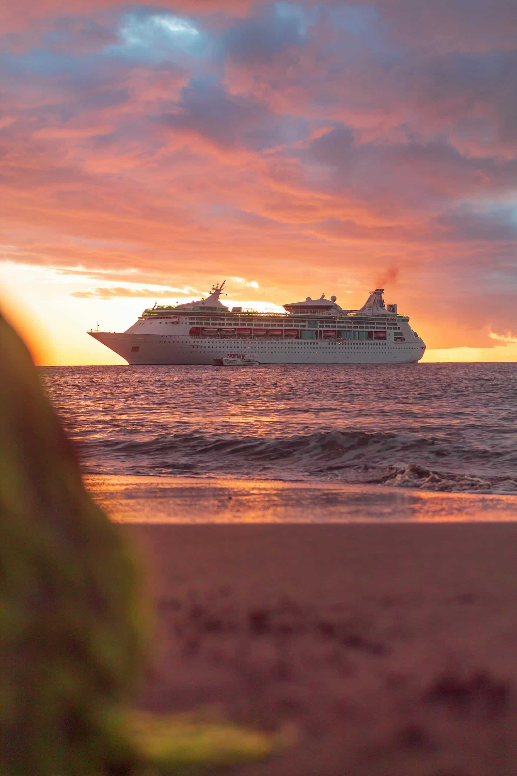 A majestic cruise ship sails through the Caribbean Sea at sunset, creating a stunning view from Bonaire's shore.
