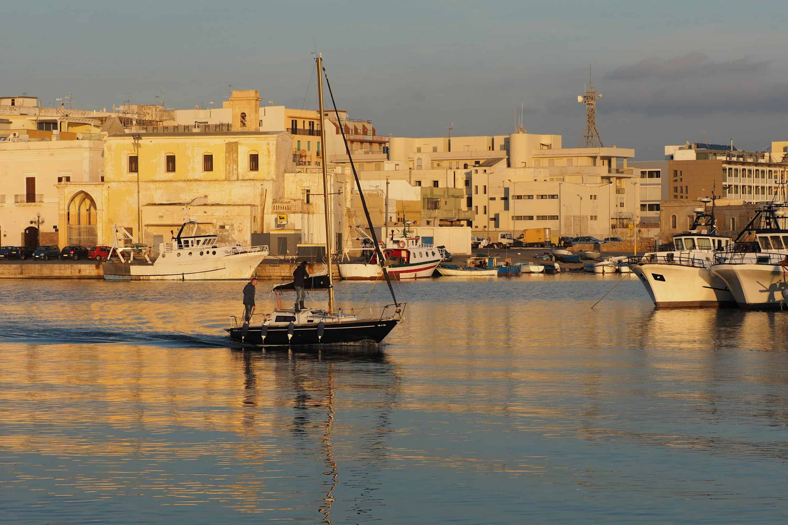 Beautiful scene of sailboats docked in Gallipoli harbor during sunset.