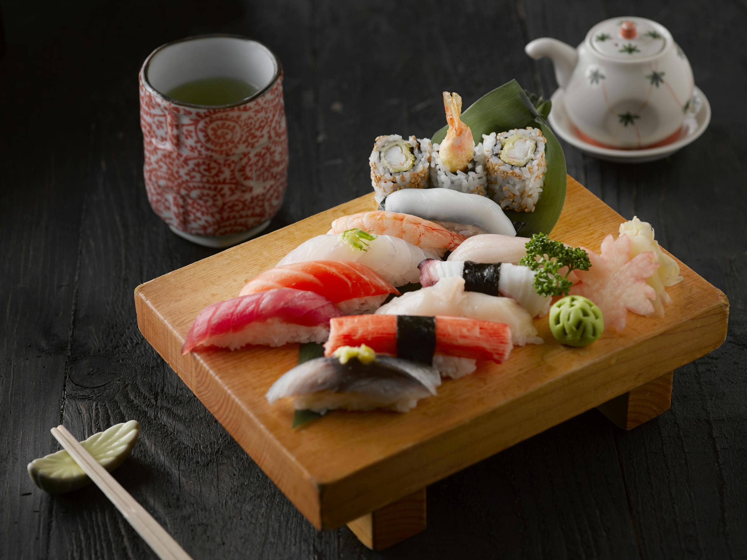 Elegant display of sushi with green tea on a wooden board, capturing authentic Japanese cuisine.