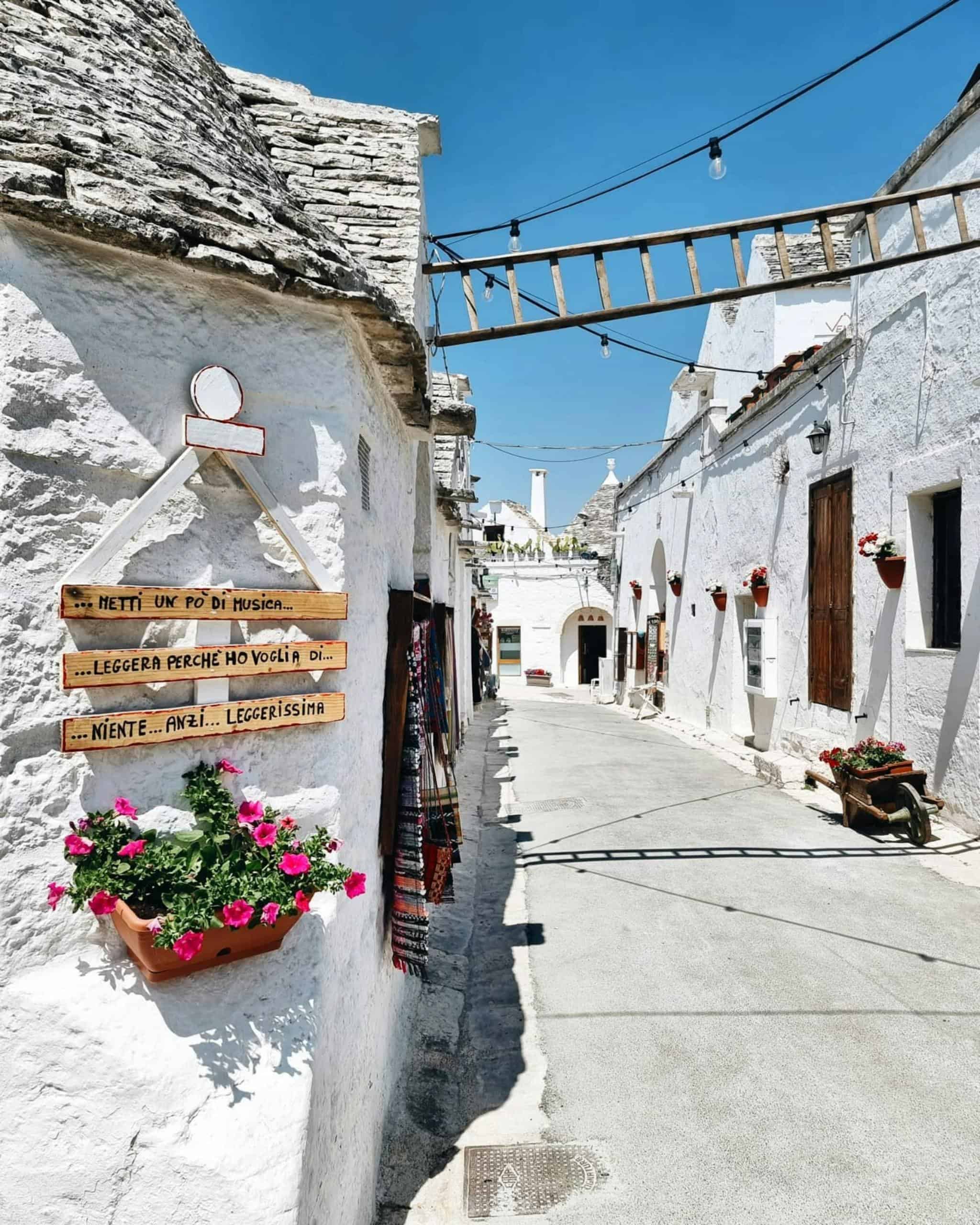 Explore the quaint white-washed streets of Alberobello on a sunny day, showcasing traditional trulli houses.