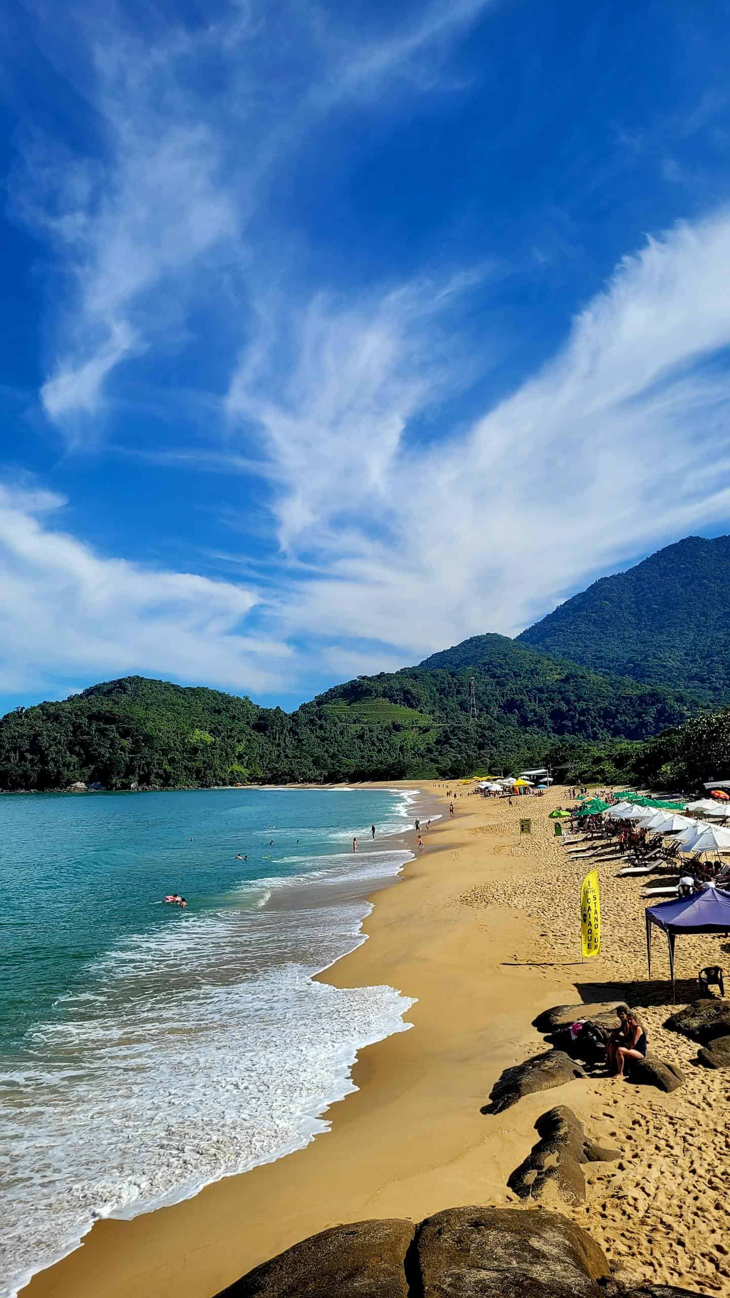 Explore the serene beaches of Ubatuba, Brazil, surrounded by lush green mountains and turquoise waters.