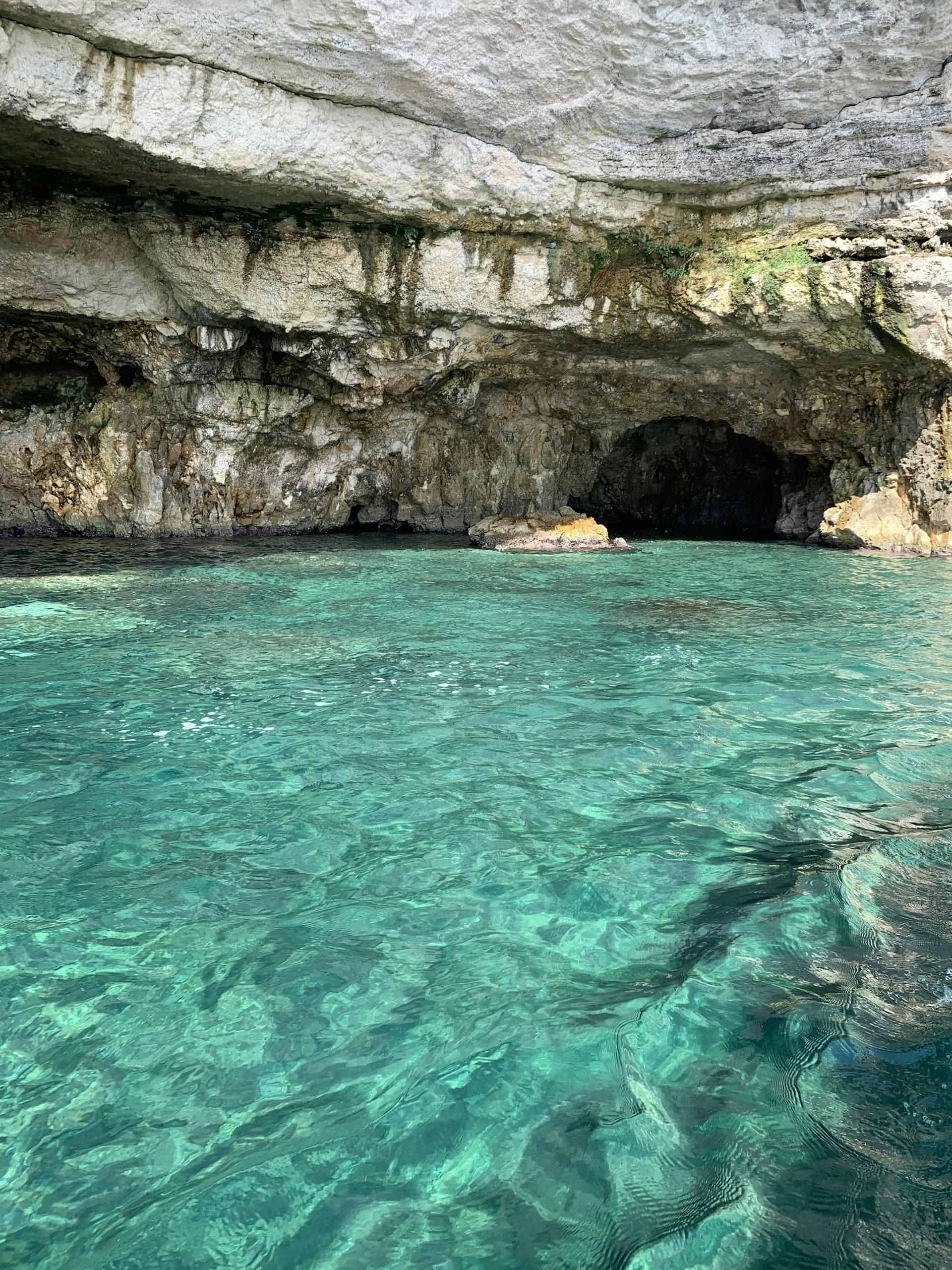 Explore the stunning turquoise waters and limestone cave formations in Puglia, Italy.
