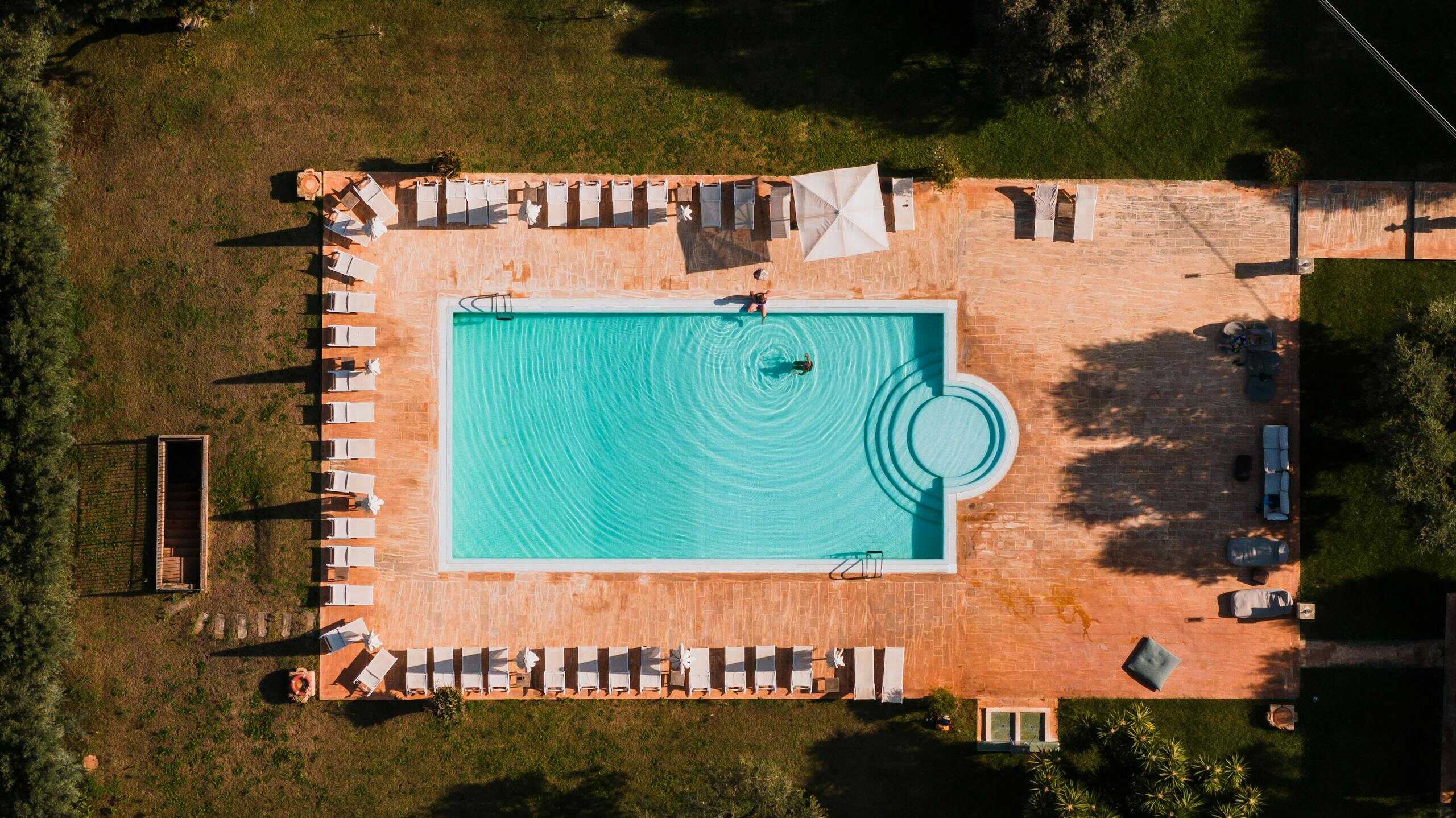 Stunning aerial view of a resort swimming pool with sunloungers in Puglia, Italy.