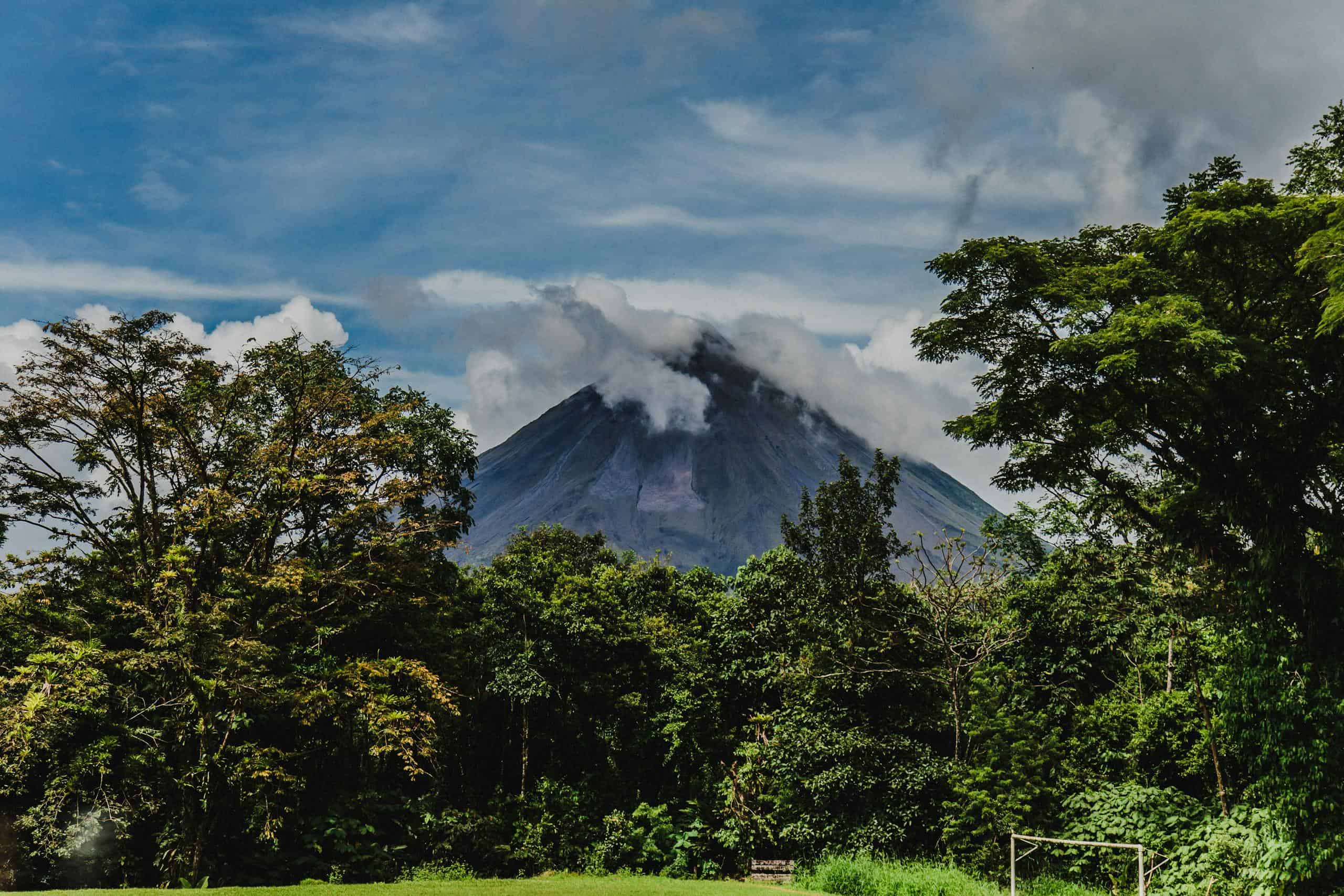 Stunning view of a lush forest with a cloud-covered volcano in the background, Costa Rica.