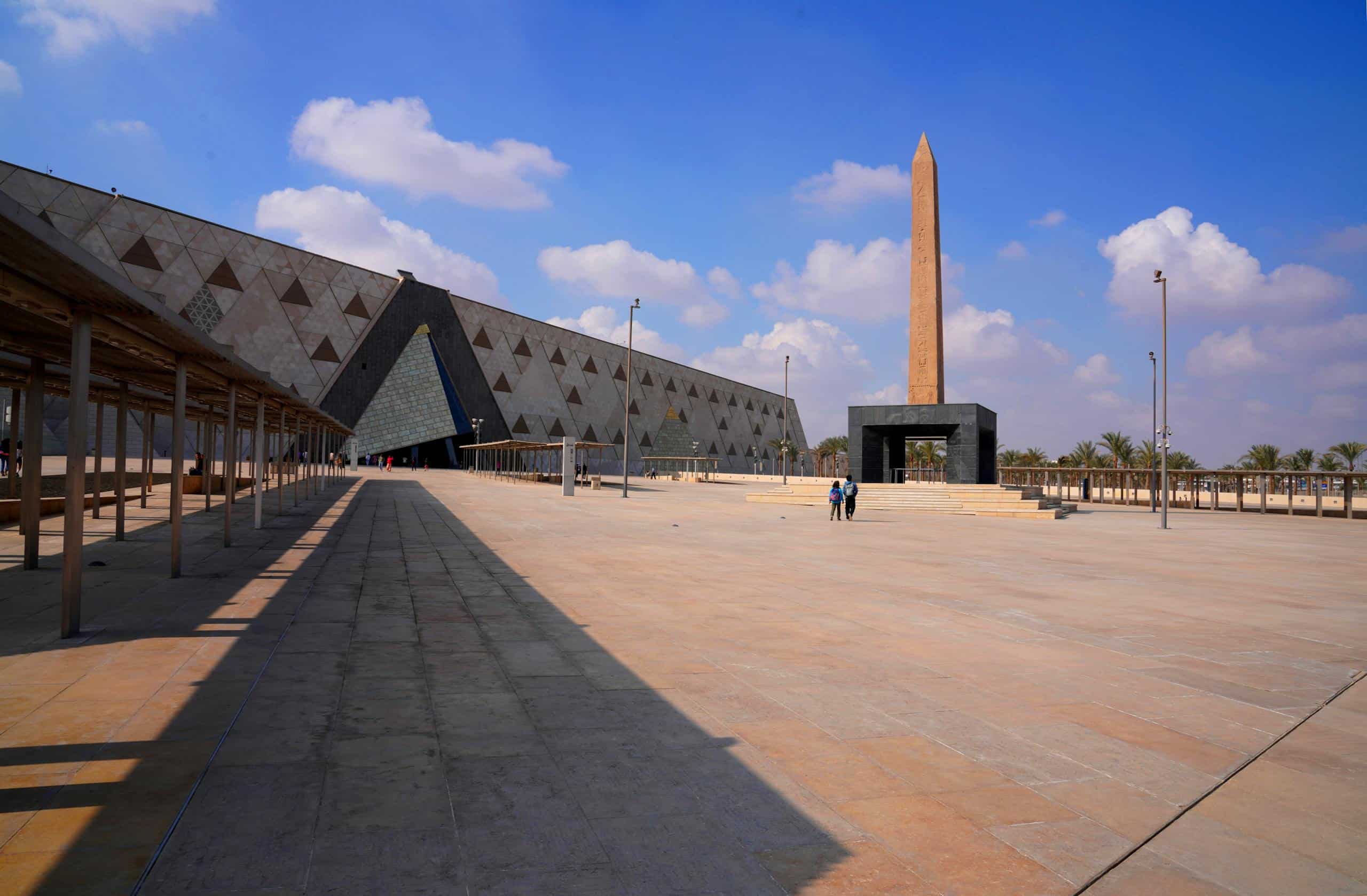 Wide-angle view of the Grand Egyptian Museum with a prominent obelisk and clear skies.