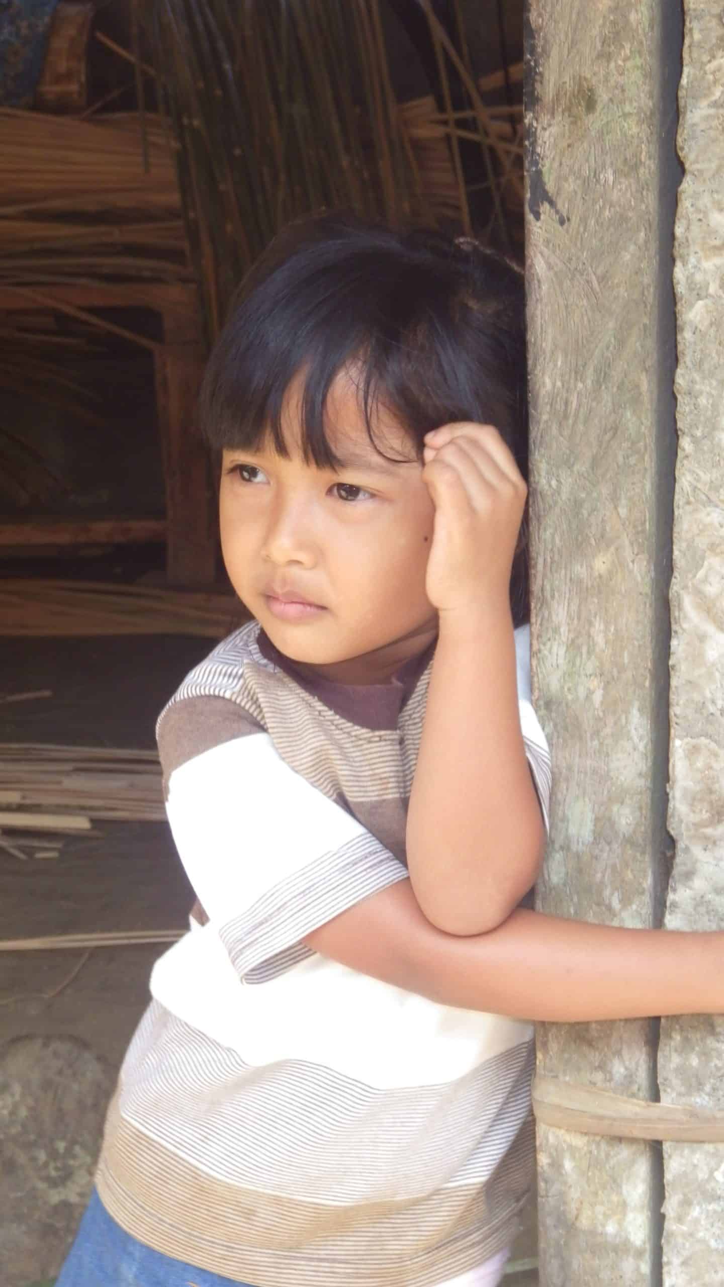 A Balinese child looks on from her family home.