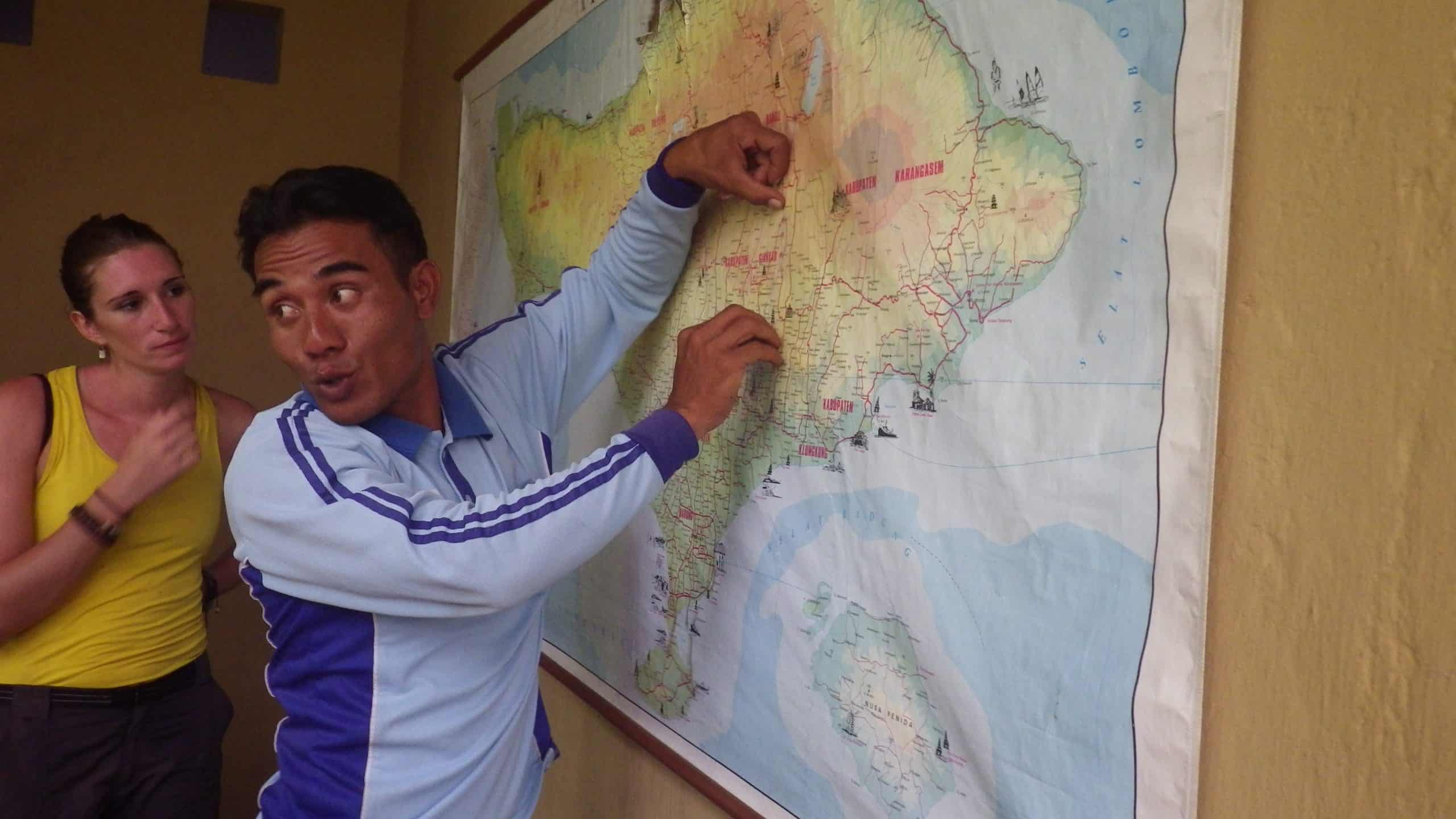 Balinese tour guide points out points of interest on a map of Bali.