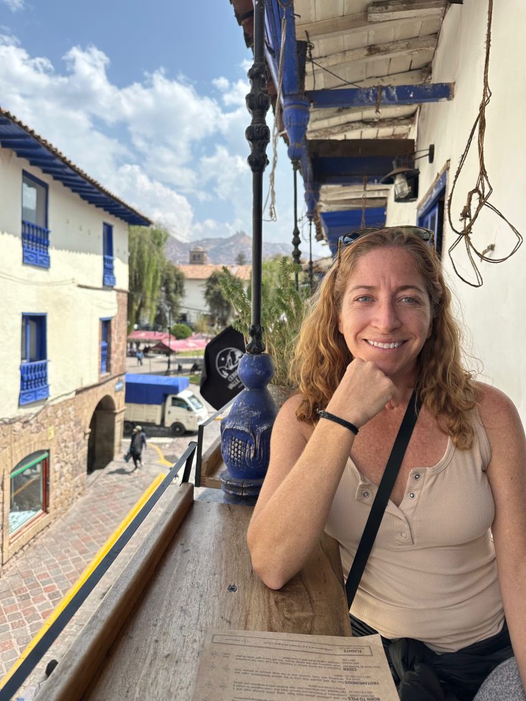 Woman sits on a balcony abroad wondering if a travel agent is worth it.