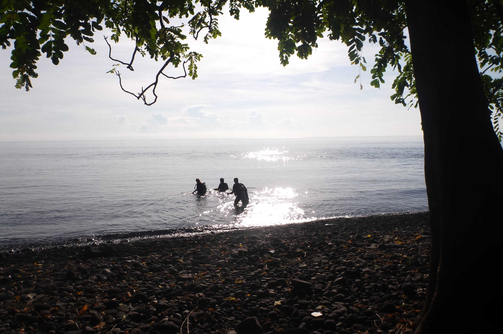 Three divers enter the water for a shore dive from Tulamben, Bali.