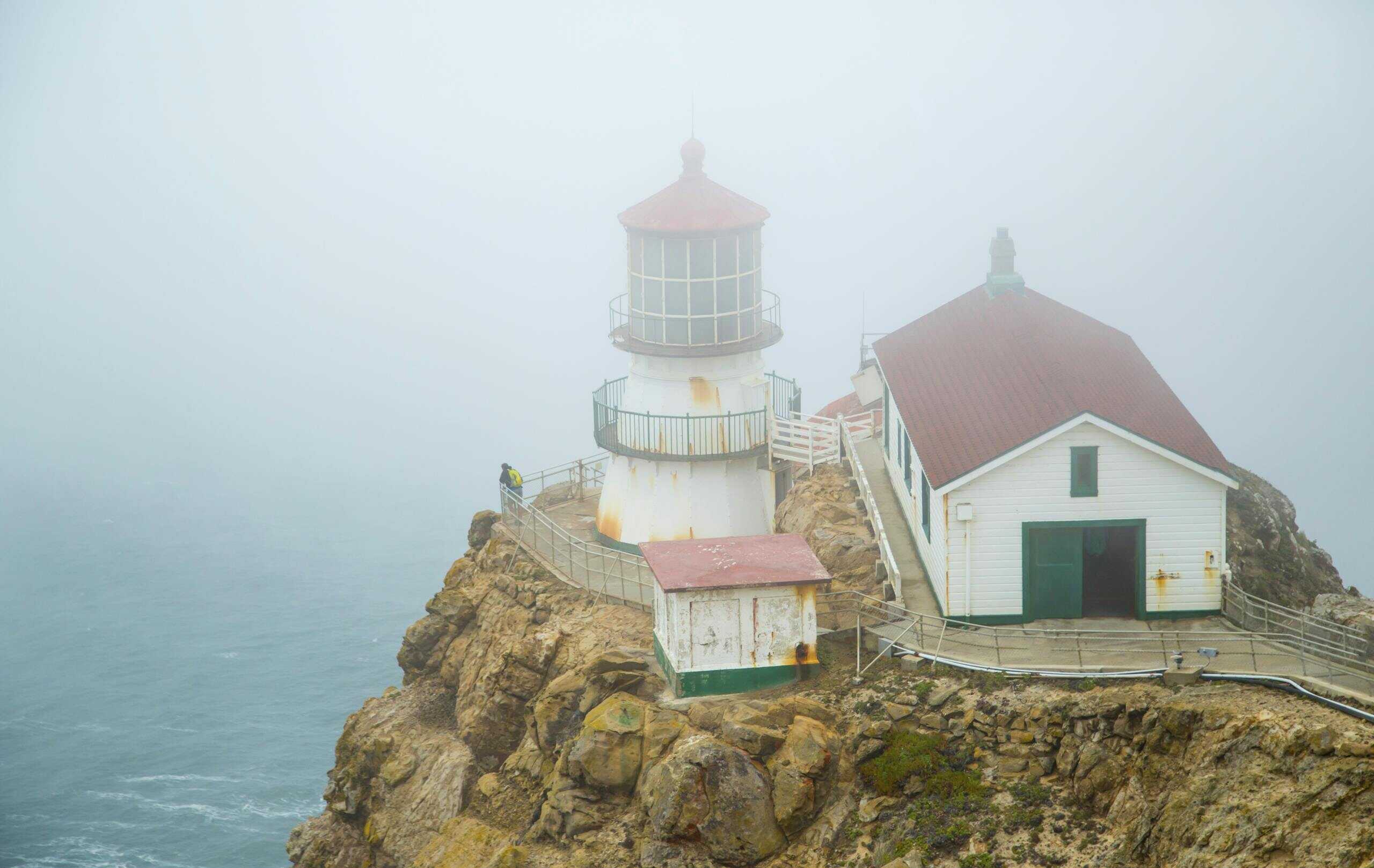 A misty view of the historic Point Reyes Lighthouse on the foggy California coast.