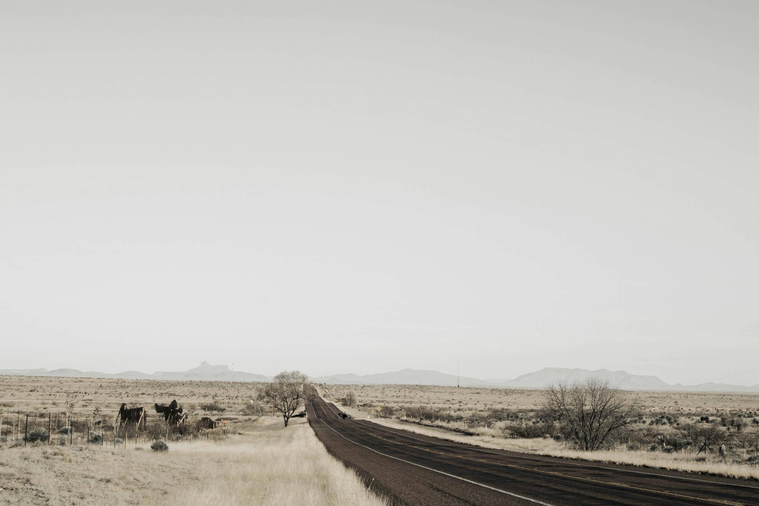 A solitary road cutting through the vast plains of Marfa, Texas, under an expansive sky.