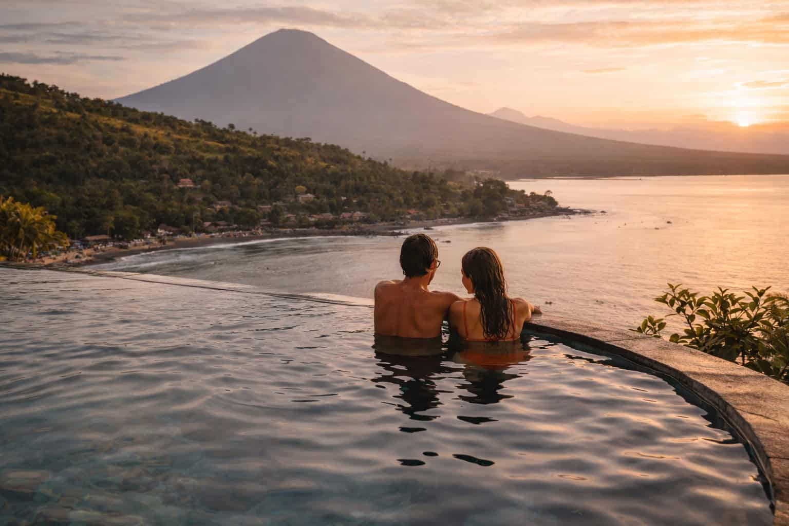 Couple shares a romantic sunset in an infinity pool perched in the cliffs above Amed, Bali.