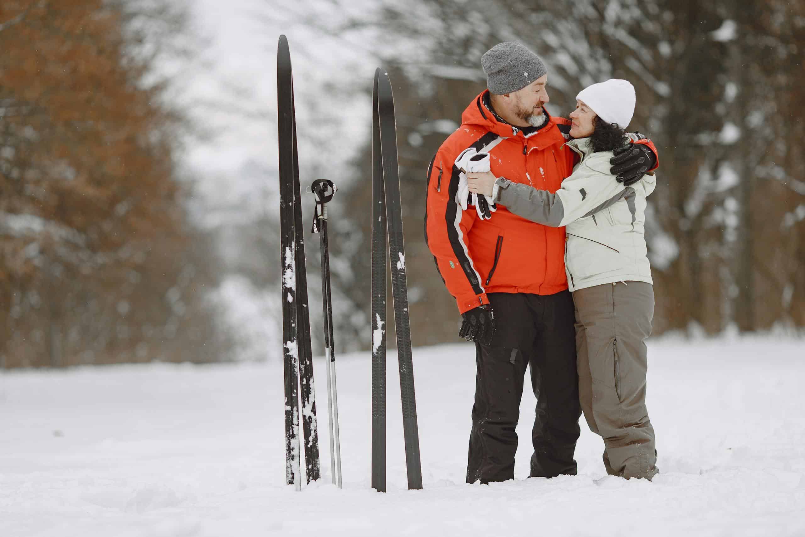 Couple embracing in snowy landscape with skis nearby, enjoying winter sports.