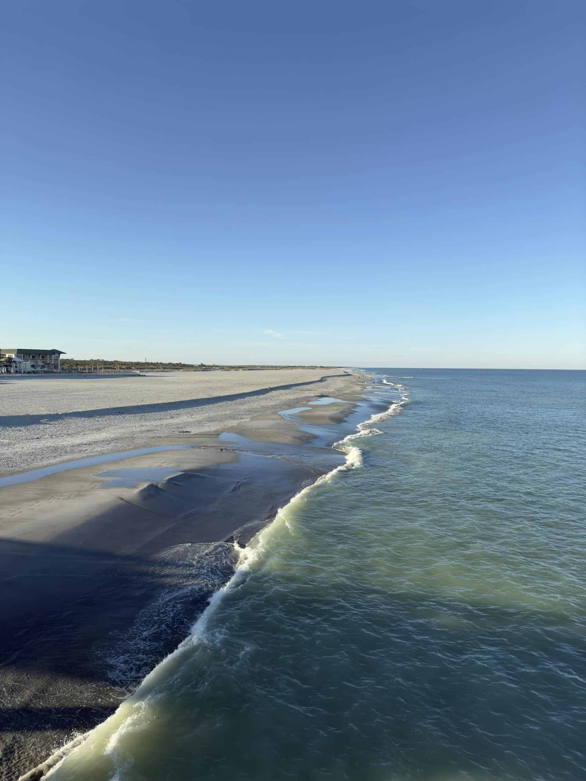 Expansive view of St. Augustine Beach with clear blue skies and calm waves.