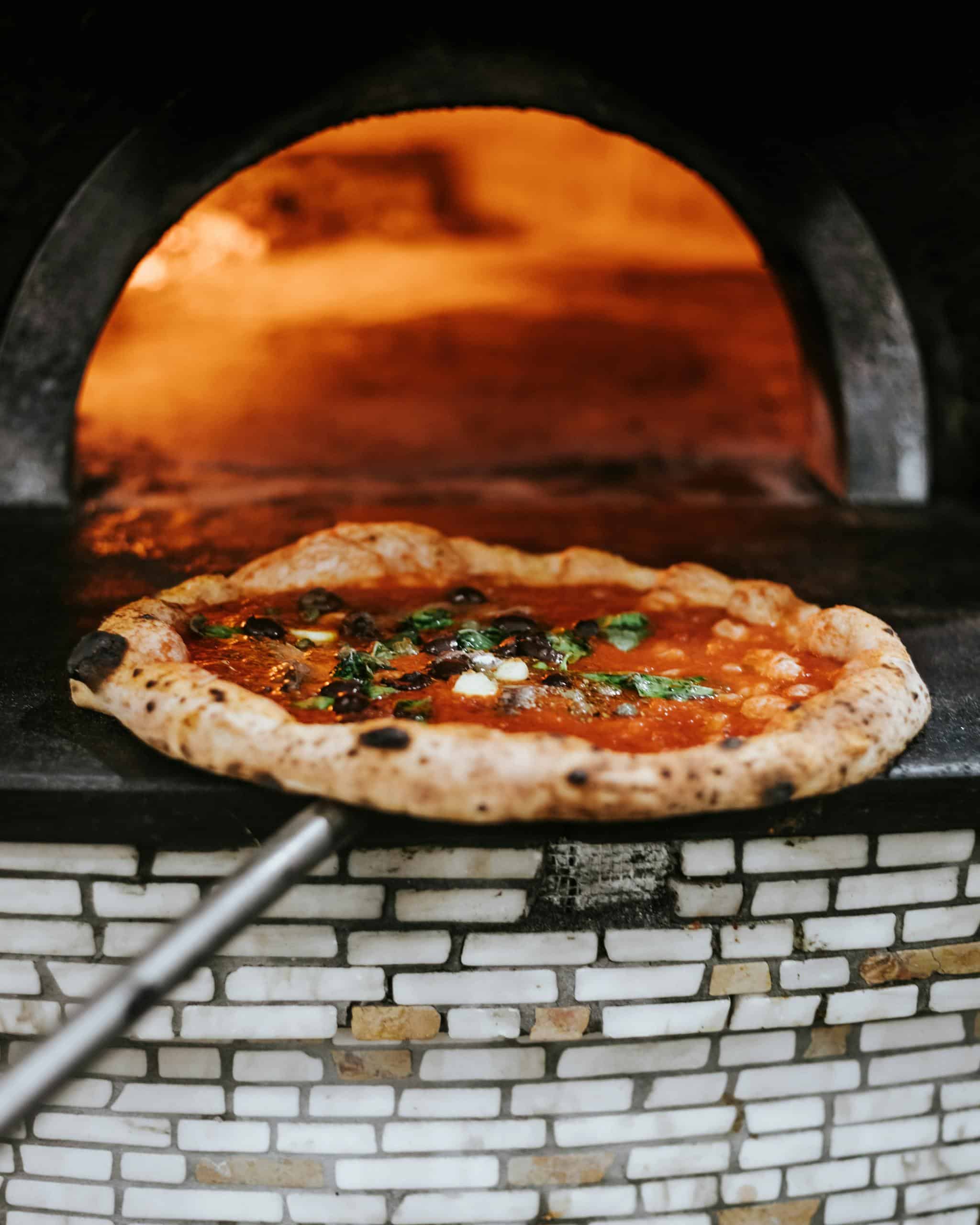 Freshly baked Neapolitan pizza emerging from a wood-fired oven in Naples.