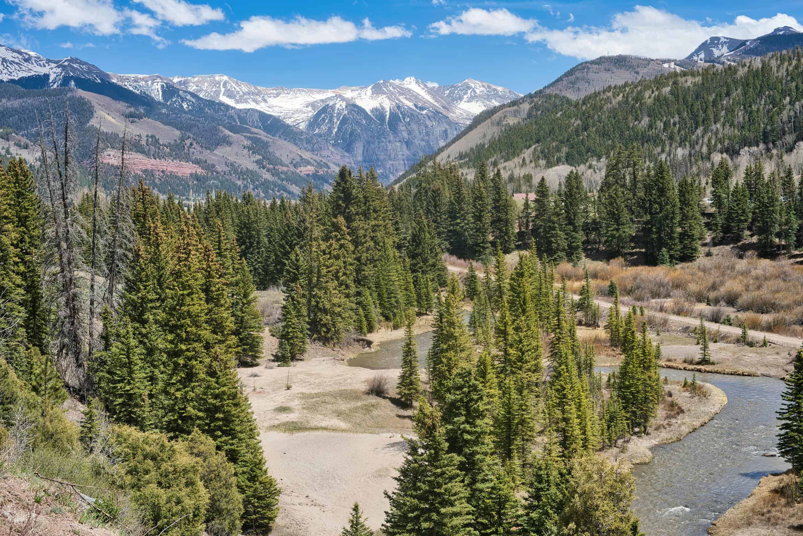 Scenic view of the majestic San Juan Mountains with lush forests and winding river in Telluride, Colorado.
