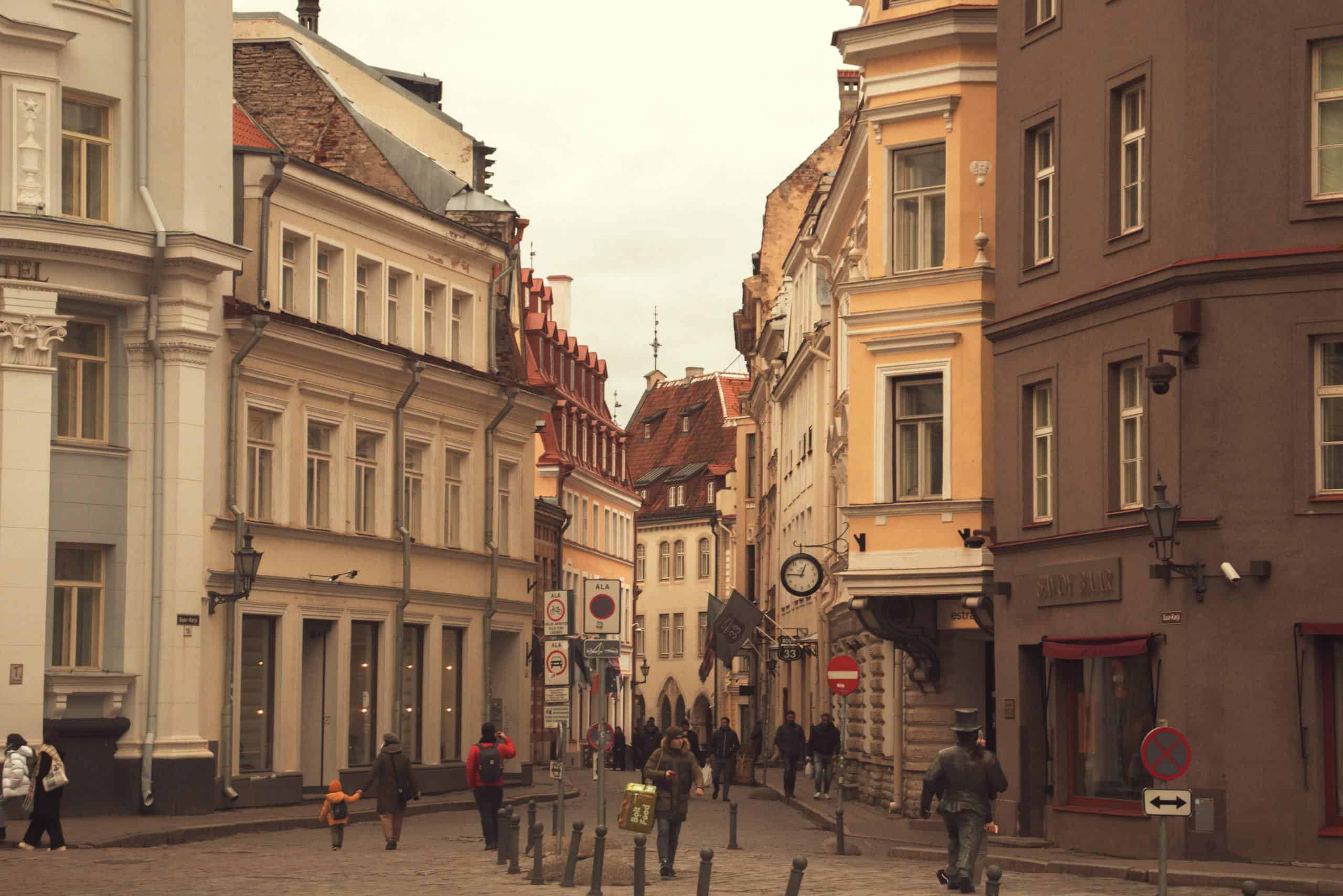 A bustling street scene in Tallinn's Old Town, featuring historic architecture and pedestrians in autumn.